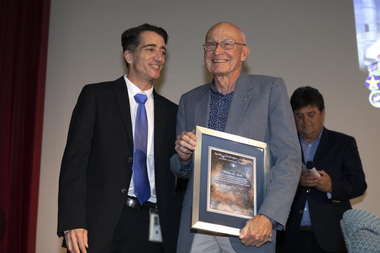 Apollo Challenger Columbia Lessons Learned Program (ACCLLP) Manager Mike Ciannilli, left, presents former space shuttle launch director Bob Sieck with a Lessons Learned Award in Kennedy Space Center’s Training Auditorium on April 12, 2019. The two men were a part of “Columbia: The Mission Continues,” an event organized by the ACCLLP. The event is part of the Space Shuttle Columbia national tour and took place on the 38th anniversary of STS-1, the first orbital spaceflight of NASA’s Space Shuttle Program. The tour launched at Kennedy and will make its way to each of the 10 NASA centers.