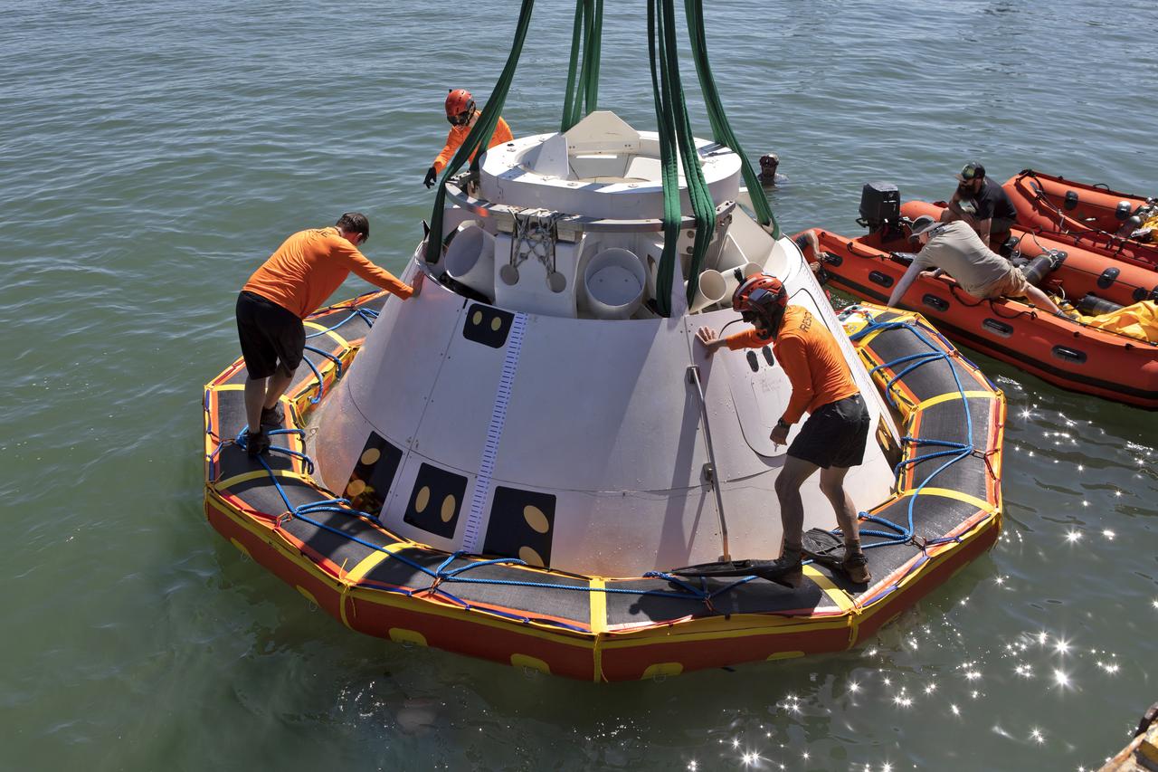 Rescue team members stand on the stabilization collar attached to the Boeing CST-100 Starliner training capsule, known as Boiler Plate 3, to perform checks during a search and rescue training exercise April 16, 2019. NASA and the Department of Defense Human Space Flight Support Office Rescue Division are conducting the exercise over the next several days at the Wharf and in the Atlantic Ocean simulating a rescue in the unlikely event of an emergency. It is the first at-sea exercise with the Starliner training capsule ahead of Boeing’s Crew Flight Test with astronauts targeted for later this year. During normal return scenarios, Boeing's Starliner will land on land in a safe zone of about 15 square miles in the Western United States. Throughout the commercial crew development phases with NASA, Boeing has performed dozens of qualification tests on its parachute and airbag systems simulating conditions on land and in the water.