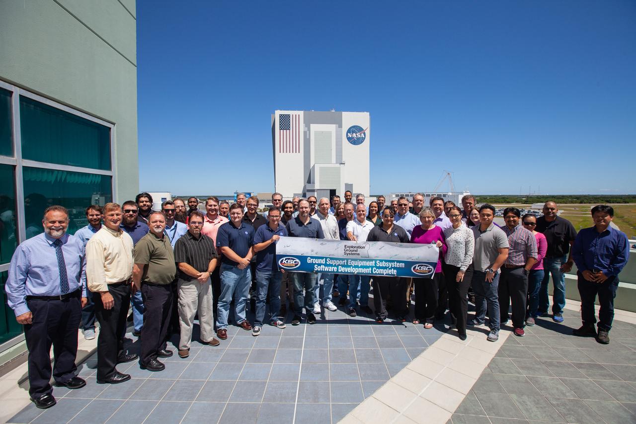 A banner signing event was held April 22, 2019, at NASA’s Kennedy Space Center in Florida, to mark the accomplishments of the Kennedy engineering team that supported the Ground Support Equipment (GSE) Subsystem Software development. The team gathered in the observation area of the Operations Support Building II with a view of the Vehicle Assembly Building behind them. This team includes the software leads, local developers, remote developers, modelers, project engineers, software quality assurance, build team members, integrators, system engineers, a chief engineer and some software managers. There are 60 unique instances of GSE Subsystem Software code. As of today, 58 of those 60 instances have completed software Level 5 Verification (L5V) and are in the process of completing Subsystem Verification & Validation.