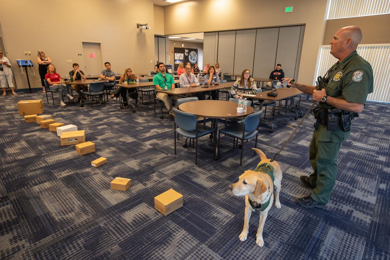Fish and Wildlife Conservation Commission (FWC) Officer Jeff Sidor presents information on FWC’s Port K9 Program to Kennedy Space Center employees in the Space Station Processing Facility Conference Center on April 23, 2019. Officer Sidor brought a special K9, Harry, to demonstrate how FWC is using specially trained dogs in airports, seaports and mail facilities to detect illegal and invasive fish and wildlife species shipping into Florida. This lunch and learn was available for employees to attend as part of Kennedy’s Earth Day events. 