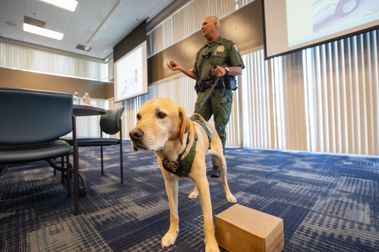 Fish and Wildlife Conservation Commission (FWC) Officer Jeff Sidor presents information on FWC’s Port K9 Program to Kennedy Space Center employees in the Space Station Processing Facility Conference Center on April 23, 2019. Officer Sidor brought a special K9, Harry, to demonstrate how FWC is using specially trained dogs in airports, seaports and mail facilities to detect illegal and invasive fish and wildlife species shipping into Florida. This lunch and learn was available for employees to attend as part of Kennedy’s Earth Day events. 