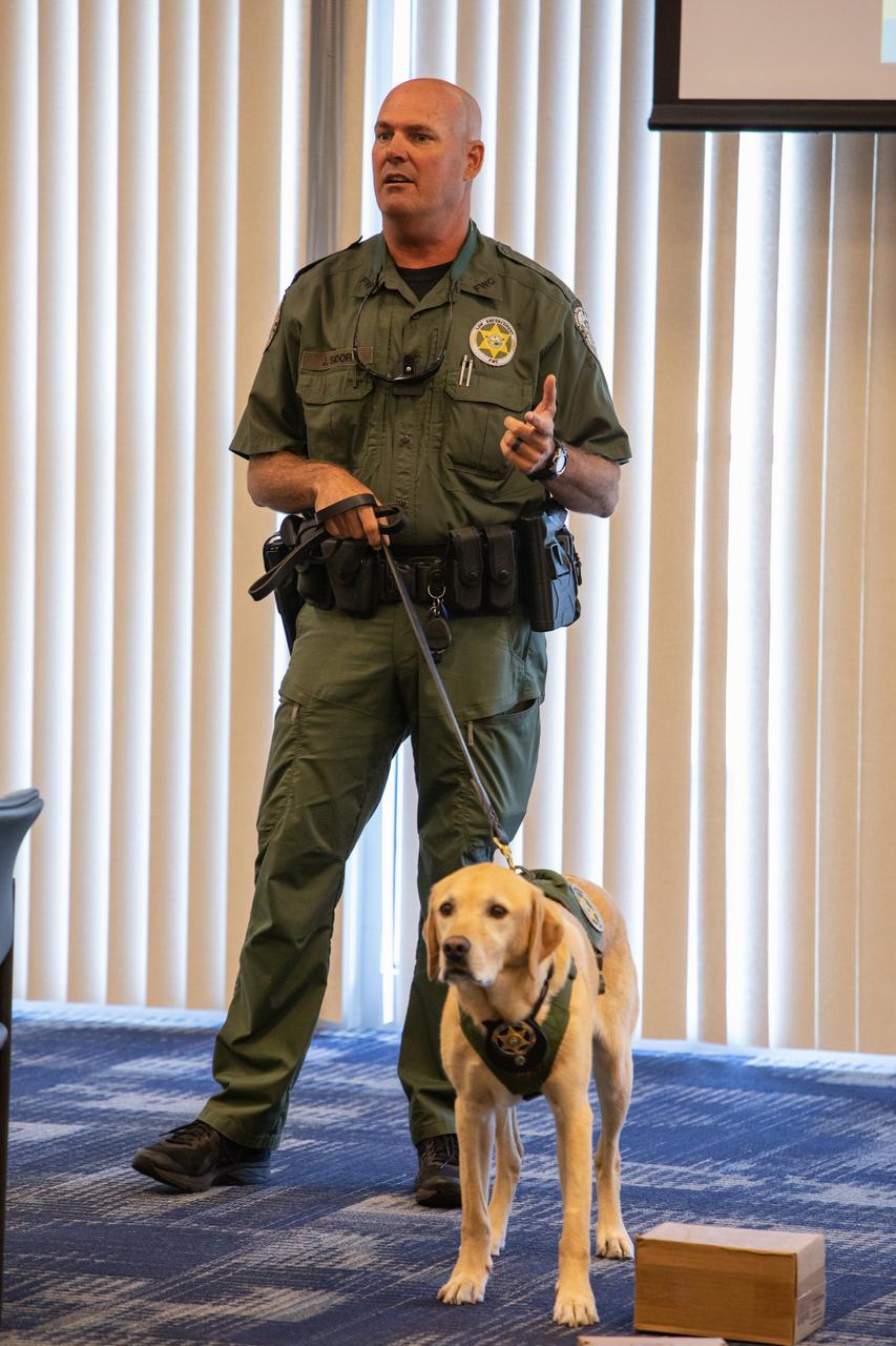 Fish and Wildlife Conservation Commission (FWC) Officer Jeff Sidor presents information on FWC’s Port K9 Program to Kennedy Space Center employees in the Space Station Processing Facility Conference Center on April 23, 2019. Officer Sidor brought a special K9, Harry, to demonstrate how FWC is using specially trained dogs in airports, seaports and mail facilities to detect illegal and invasive fish and wildlife species shipping into Florida. The demonstration involved Harry distinguishing which box, among many, contained a turtle shell. This lunch and learn was available for employees to attend as part of Kennedy’s Earth Day events. 