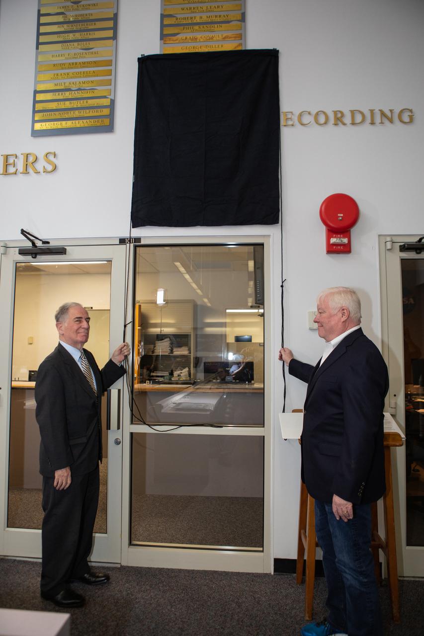 Vic Ratner, left, and Todd Halvorson unveil their names, along with the names of Jim Banke and Peter Cosgrove, now on display on The Chroniclers wall at Kennedy Space Center’s NASA News Center in Florida during a ceremony May 3, 2019. Banke, Halvorson, Ratner and Cosgrove were honored as members of The Chroniclers, which recognizes retirees of the news and communications business who have helped spread news of American space exploration from Kennedy for 10 years or more. They were selected by a committee of their peers on March 25. 