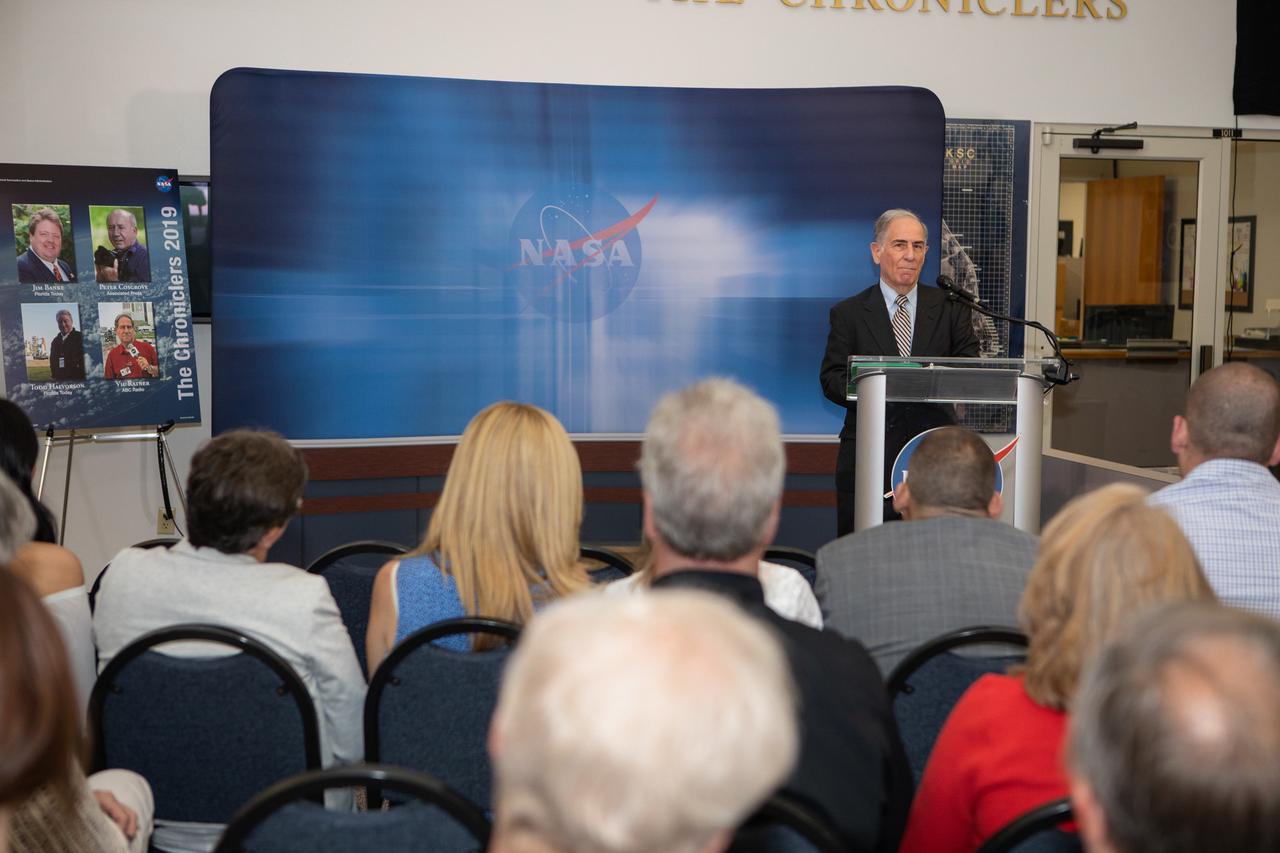 Vic Ratner, former radio broadcaster for ABC Radio, addresses a crowd of family and friends, current and former NASA officials, and space journalists after he is inducted as a 2019 Chronicler during a ceremony at Kennedy Space Center’s NASA News Center in Florida on May 3, 2019. Also honored as Chroniclers were journalists Jim Banke and Todd Halvorson, and photographer Peter Cosgrove. The Chroniclers recognizes retirees of the news and communications business who have helped spread news of American space exploration from Kennedy for 10 years or more. The group of four was selected by a committee of their peers on March 25. Their names were engraved on brass strips and added to The Chroniclers wall display in the news center and were unveiled during the ceremony. 