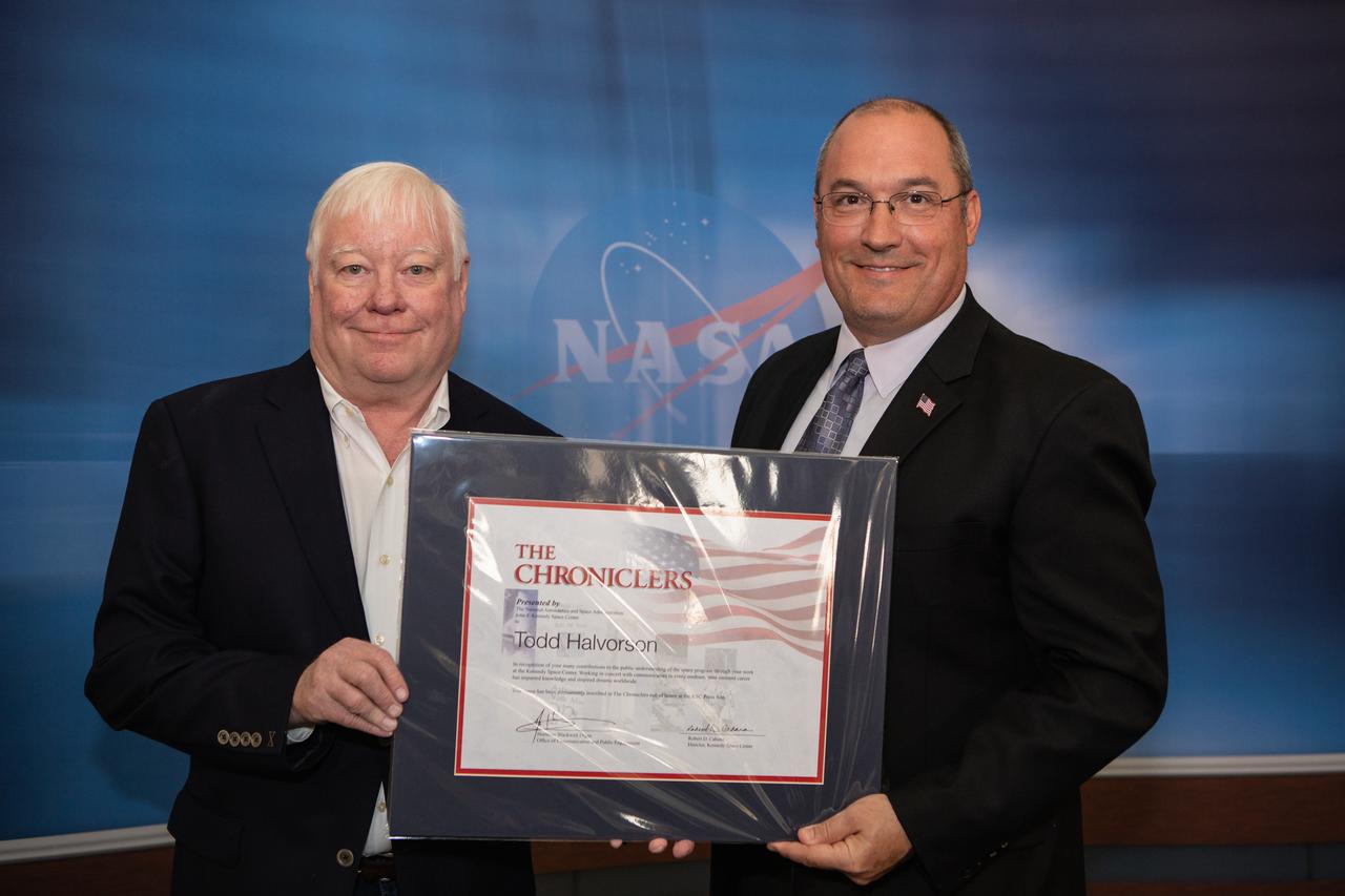 NASA Public Affairs Officer Greg Harland, right, poses for a photograph with newly inducted Chronicler Todd Halvorson during a ceremony at Kennedy Space Center’s NASA News Center in Florida on May 3, 2019. Halvorson covered the space program from Kennedy for more than three decades and also was senior aerospace reporter at Florida Today. Also inducted as members were journalist Jim Banke, radio broadcaster Vic Ratner and photographer Peter Cosgrove. They were selected by a committee of their peers on March 25. The Chroniclers recognizes retirees of the news and communications business who have helped spread news of American space exploration from Kennedy for 10 years or more. 
