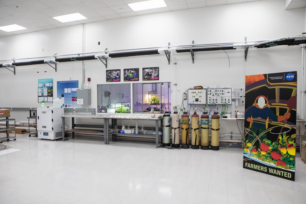 Two plant growth experiments are in view behind glass in a laboratory inside the Space Station Processing Facility (SSPF) at NASA’s Kennedy Space Center in Florida, on May 16, 2019. The center is celebrating the SSPF’s 25th anniversary. The facility was built to process elements for the International Space Station. Now it is providing support for current and future NASA and commercial provider programs, including Commercial Resupply Services, Artemis 1, sending the first woman and next man to the Moon, and deep space destinations including Mars.