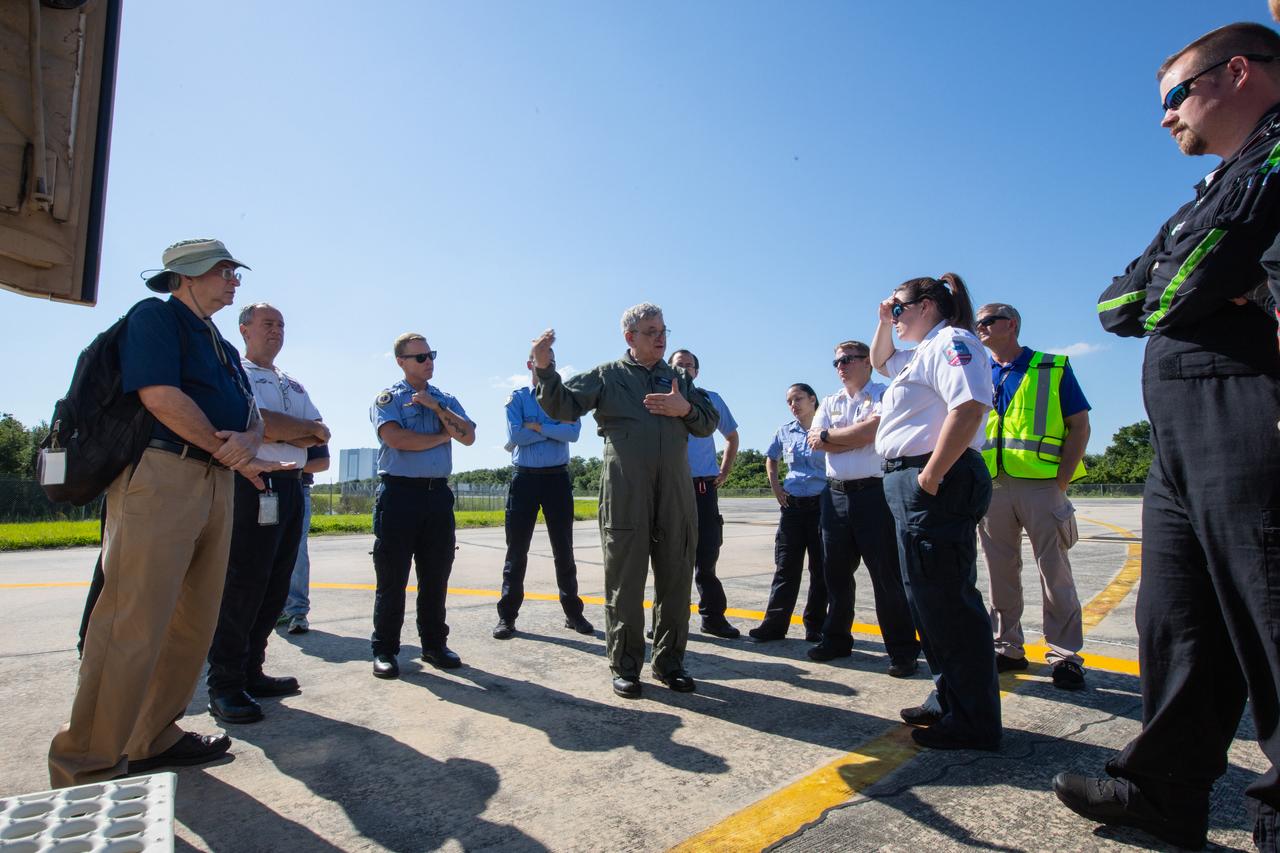 KEMCON physician Dr. Dan Woodard speaks to Kennedy Space Center personnel and American Medical Response (AMR) contractor paramedics gathered at the Florida spaceport’s Shuttle Landing Facility on May 17, 2019, for a medical support training course. The course was designed to familiarize the AMR paramedics with the center’s Triage Forces deployment, which included medical team members, fire/rescue personnel, environmental health specialists and flight operations crew members, as well as a helicopter, Mine Resistant Ambush Protected (MRAP) tactical vehicle, fire pumper truck and triage vehicles. The AMR paramedics will assist the agency in contingency planning for the return of human spaceflight from Kennedy.
