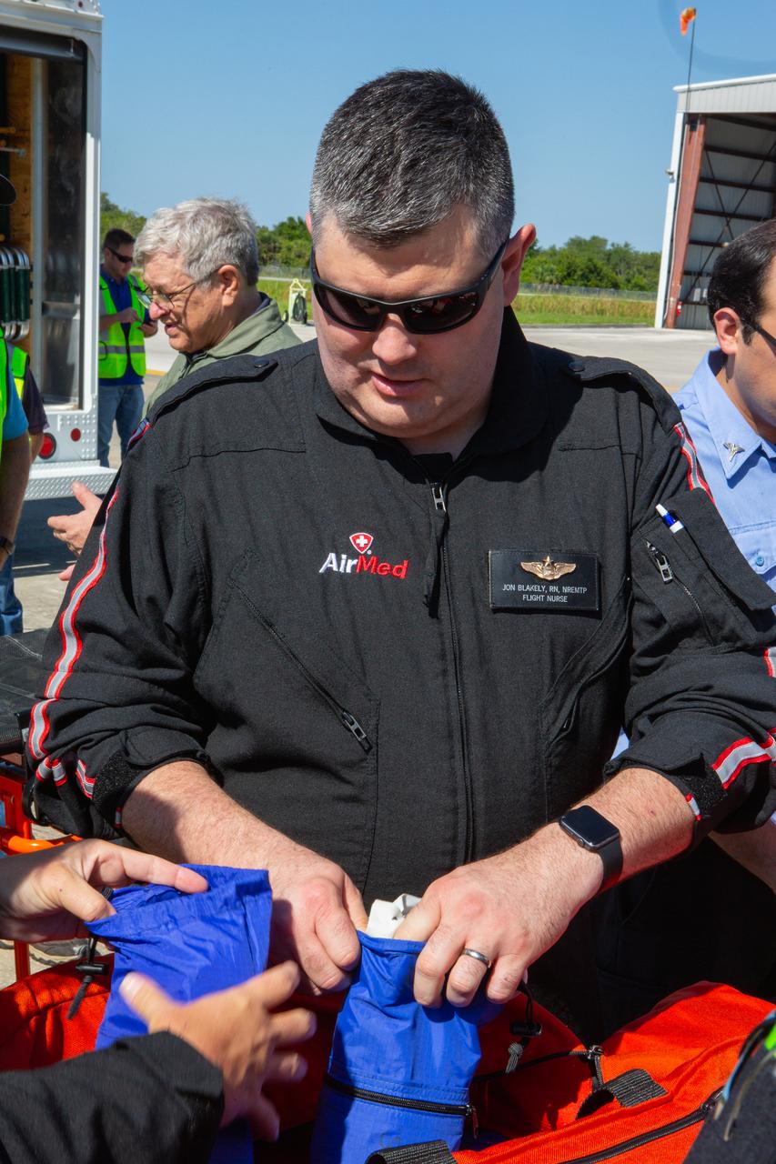 Jon Blakely, an AirMed flight nurse, joins Kennedy Space Center personnel and American Medical Response (AMR) contractor paramedics at the Florida spaceport’s Shuttle Landing Facility on May 17, 2019, for a medical support training course. Signs in the foreground indicate the “dirty side,” where patient off-loading and decontamination would take place, and the “clean side,” used for patient evaluation and medevac. The course was designed to familiarize the AMR paramedics with the center’s Triage Forces deployment, which included medical team members, fire/rescue personnel, environmental health specialists and flight operations crew members, as well as a helicopter, Mine Resistant Ambush Protected (MRAP) tactical vehicle, fire pumper truck and triage vehicles. The AMR paramedics will assist the agency in contingency planning for the return of human spaceflight from Kennedy.