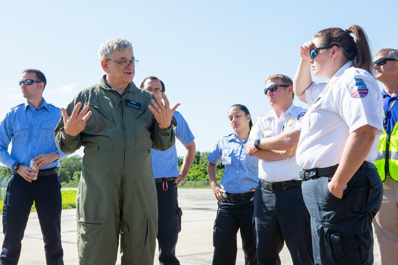 KEMCON physician Dr. Dan Woodard speaks to Kennedy Space Center personnel and American Medical Response (AMR) contractor paramedics gathered at the Florida spaceport’s Shuttle Landing Facility on May 17, 2019, for a medical support training course. The course was designed to familiarize the AMR paramedics with the center’s Triage Forces deployment, which included medical team members, fire/rescue personnel, environmental health specialists and flight operations crew members, as well as a helicopter, Mine Resistant Ambush Protected (MRAP) tactical vehicle, fire pumper truck and triage vehicles. The AMR paramedics will assist the agency in contingency planning for the return of human spaceflight from Kennedy.