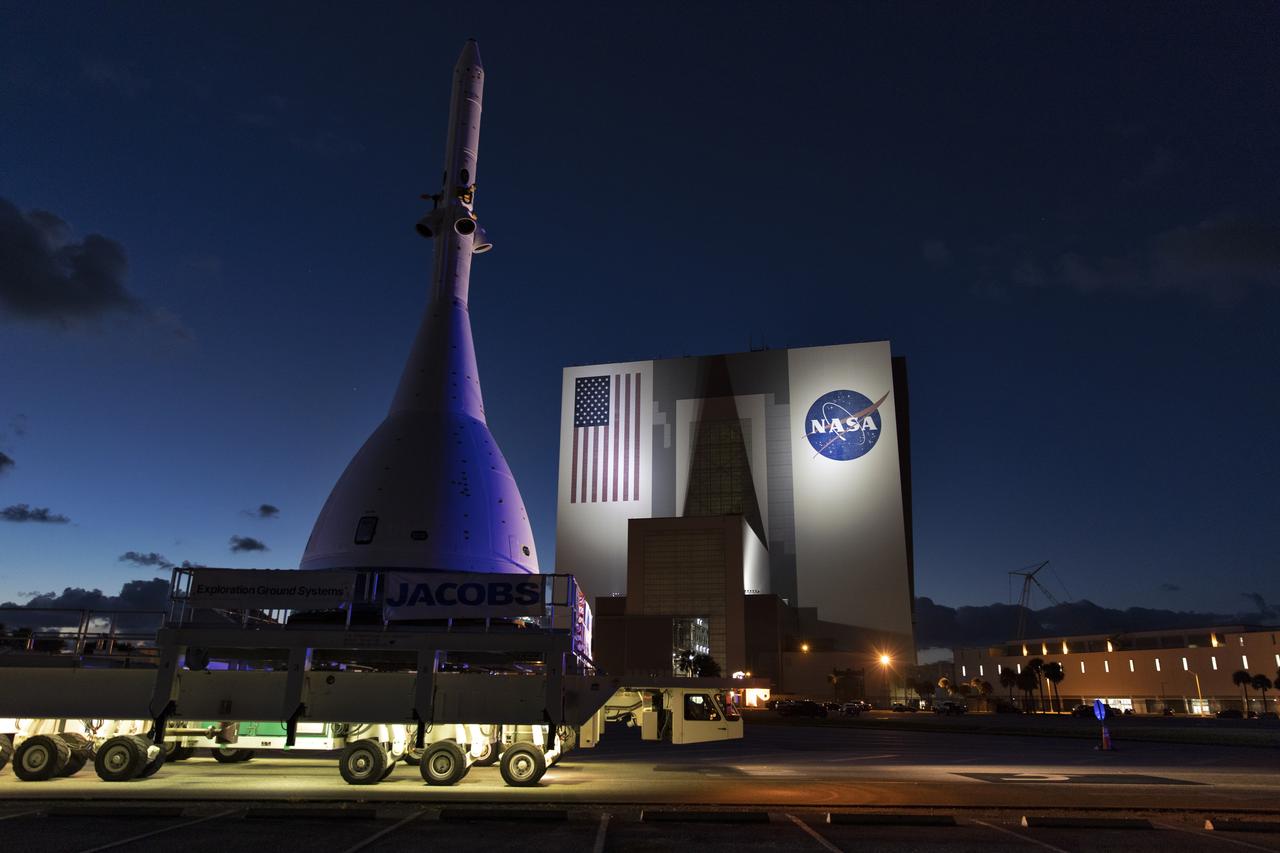 The test version of Orion attached to the Launch Abort System for the Ascent Abort-2 (AA-2) flight test passes by the iconic Vehicle Assembly Building at NASA’s Kennedy Space Center in Florida on May 22, 2019, during its 21.5 mile trek to Space Launch Complex 46 at Cape Canaveral Air Force Station in preparation for its launch this summer. In the background is the iconic Vehicle Assembly Building. During AA-2, a test version of Orion will launch on a booster to more than six miles in altitude, where Orion’s launch abort system will pull the capsule and its crew away to safety if an emergency occurs during ascent on the Space Launch System rocket. The AA-2 elements will be stacked together at the launch pad over the next several weeks. The launch is planned for July 2 and is a critical safety test that helps pave the way for Artemis missions near the Moon, and will enable astronauts to set foot on the lunar surface by 2024.