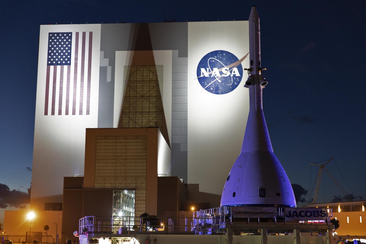 The test version of Orion attached to the Launch Abort System for the Ascent Abort-2 (AA-2) flight test passes by the iconic Vehicle Assembly Building at NASA’s Kennedy Space Center in Florida on May 22, 2019, during its 21.5 mile trek to Space Launch Complex 46 at Cape Canaveral Air Force Station in preparation for its launch this summer. In the background is the iconic Vehicle Assembly Building. During AA-2, a test version of Orion will launch on a booster to more than six miles in altitude, where Orion’s launch abort system will pull the capsule and its crew away to safety if an emergency occurs during ascent on the Space Launch System rocket. The AA-2 elements will be stacked together at the launch pad over the next several weeks. The launch is planned for July 2 and is a critical safety test that helps pave the way for Artemis missions near the Moon, and will enable astronauts to set foot on the lunar surface by 2024.