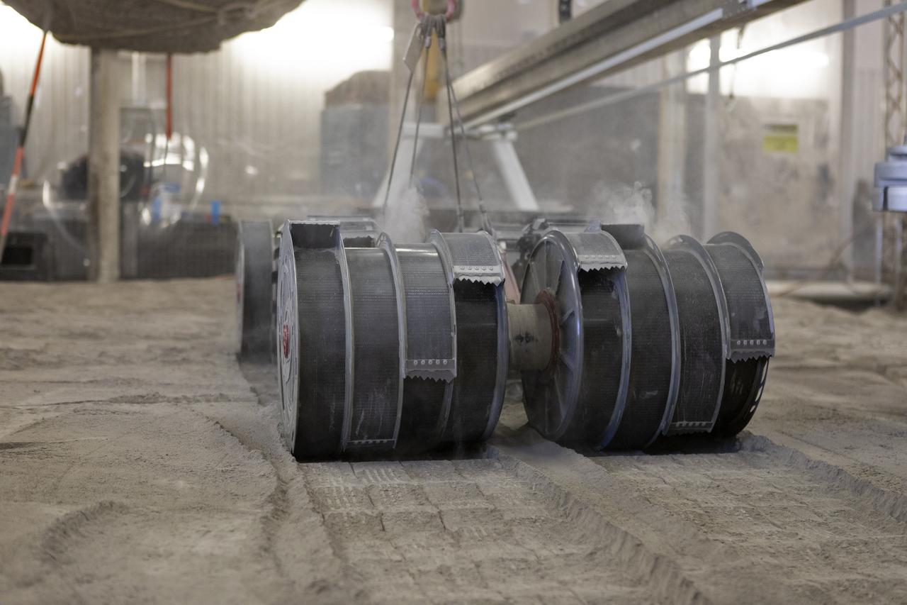 A team from the Granular Mechanics and Regolith Operations Lab tests the Regolith Advanced Surface Systems Operations Robot (RASSOR) in the regolith bin inside Swamp Works at NASA’s Kennedy Space Center in Florida on June 5, 2019. Tests use a gravity assist offload system to simulate reduced gravity conditions found on the Moon. On the surface of the Moon, mining robots like RASSOR will excavate the regolith and take the material to a processing plant where usable elements such as hydrogen, oxygen and water can be extracted for life support systems. RASSOR can scoop up icy regolith which can be used to make operations on the Moon sustainable.