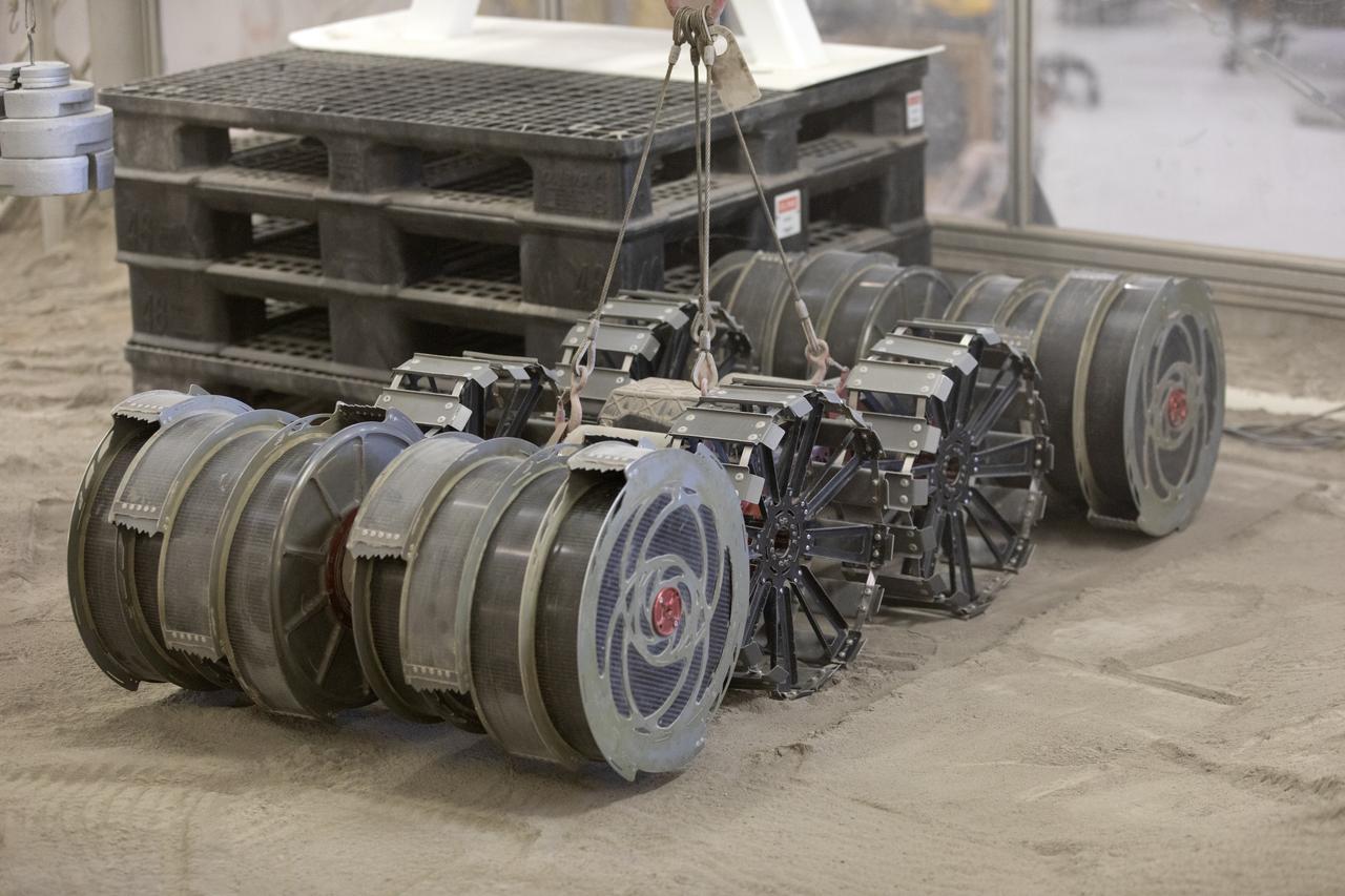 A team from the Granular Mechanics and Regolith Operations Lab tests the Regolith Advanced Surface Systems Operations Robot (RASSOR) in the regolith bin inside Swamp Works at NASA’s Kennedy Space Center in Florida on June 5, 2019. Tests use a gravity assist offload system to simulate reduced gravity conditions found on the Moon. On the surface of the Moon, mining robots like RASSOR will excavate the regolith and take the material to a processing plant where usable elements such as hydrogen, oxygen and water can be extracted for life support systems. RASSOR can scoop up icy regolith which can be used to make operations on the Moon sustainable.