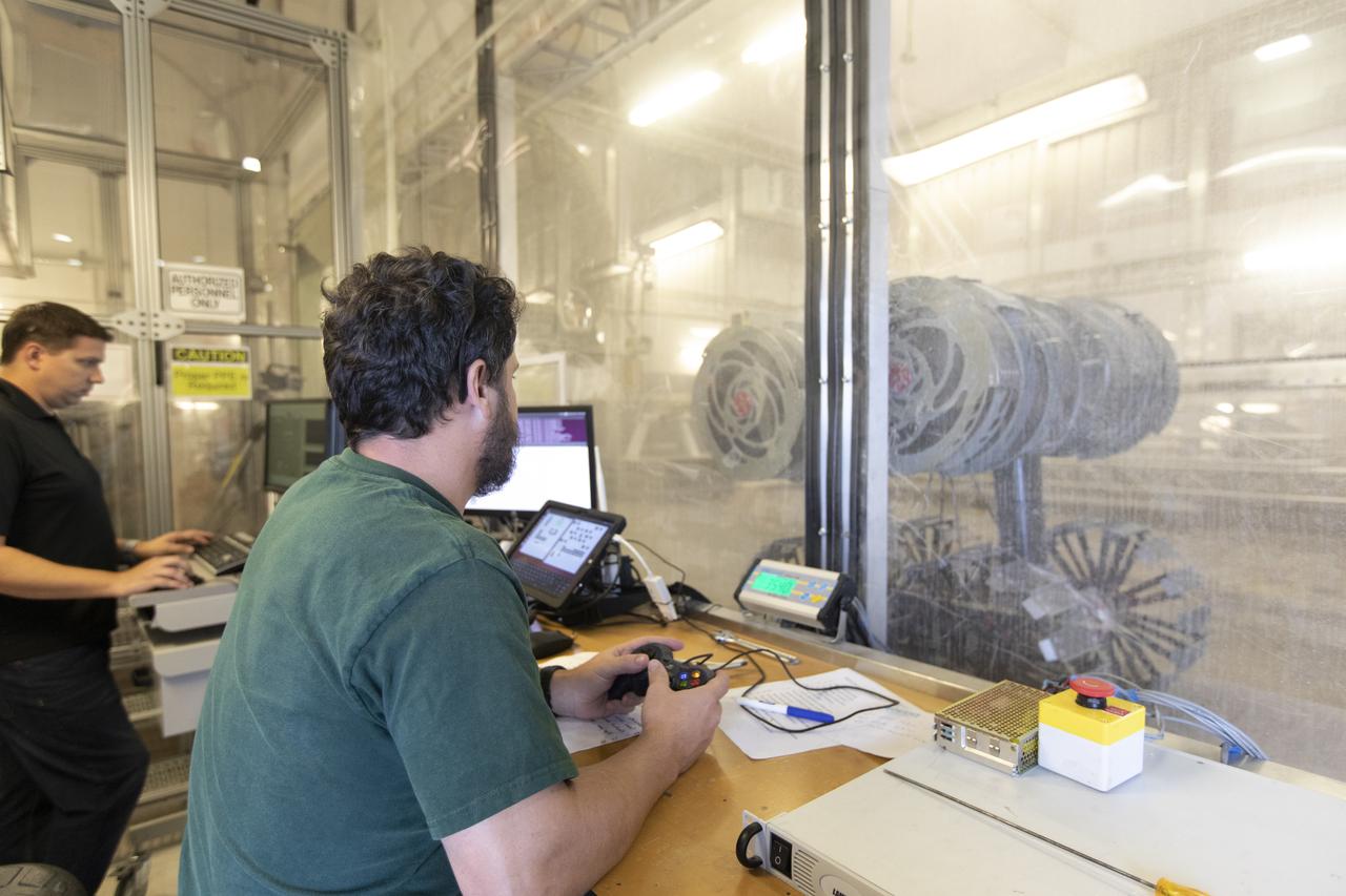 AJ Nick, a robotic engineer with the Granular Mechanics and Regolith Operations Lab, monitors the Regolith Advanced Surface Systems Operations Robot (RASSOR) from a control room during testing in the regolith bin inside Swamp Works at NASA’s Kennedy Space Center in Florida on June 5, 2019. Tests use a gravity assist offload system to simulate reduced gravity conditions found on the Moon. On the surface of the Moon, mining robots like RASSOR will excavate the regolith and take the material to a processing plant where usable elements such as hydrogen, oxygen and water can be extracted for life support systems. RASSOR can scoop up icy regolith which can be used to make operations on the Moon sustainable.