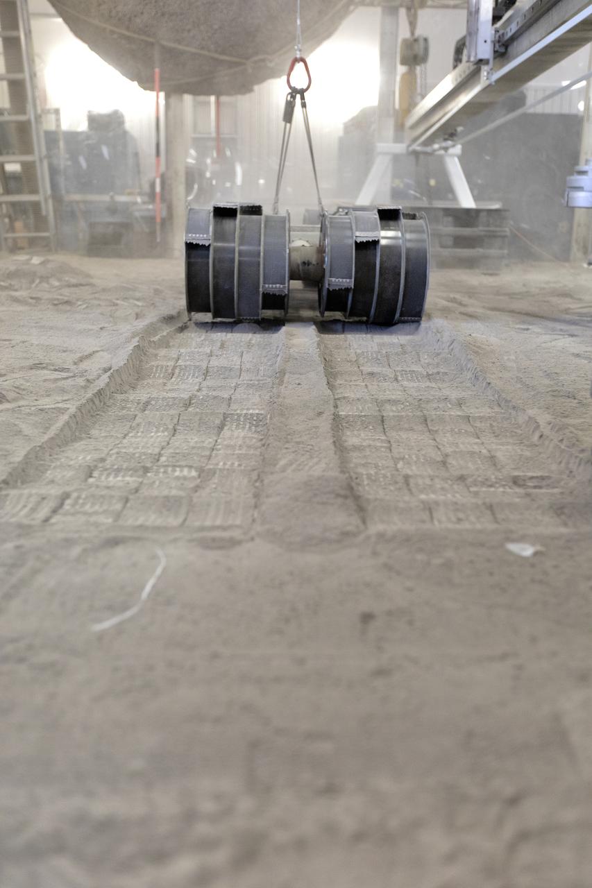 A team from the Granular Mechanics and Regolith Operations Lab tests the Regolith Advanced Surface Systems Operations Robot (RASSOR) in the regolith bin inside Swamp Works at NASA’s Kennedy Space Center in Florida on June 5, 2019. Tests use a gravity assist offload system to simulate reduced gravity conditions found on the Moon. On the surface of the Moon, mining robots like RASSOR will excavate the regolith and take the material to a processing plant where usable elements such as hydrogen, oxygen and water can be extracted for life support systems. RASSOR can scoop up icy regolith which can be used to make operations on the Moon sustainable.