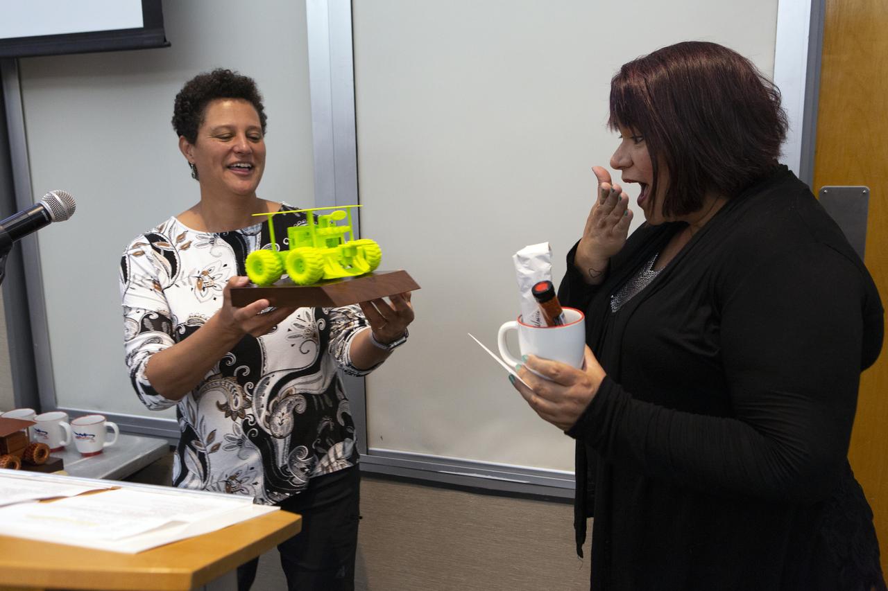Melanie Moses, a professor of computer science at the University of New Mexico, presents a small replica of a Swarmie robot to Theresa Martinez, engagement manager of the Minority University Research and Education Program, during an awards ceremony at the Kennedy Space Center Visitor Complex in Florida on June 12, 2019. Swarmathon University Competition students and their mentors were at Kennedy to participate in a student/mentor panel, hear from speakers, get a behind-the-scenes tour of Kennedy Space Center, dine with an astronaut and receive awards. During Swarmathon University Challenge IV, students developed algorithms for robotic swarms that are robust and adaptable like the foraging strategies of ant colonies. The fourth and final Swarmathon was a combined virtual and physical competition, hosted by the University of New Mexico.