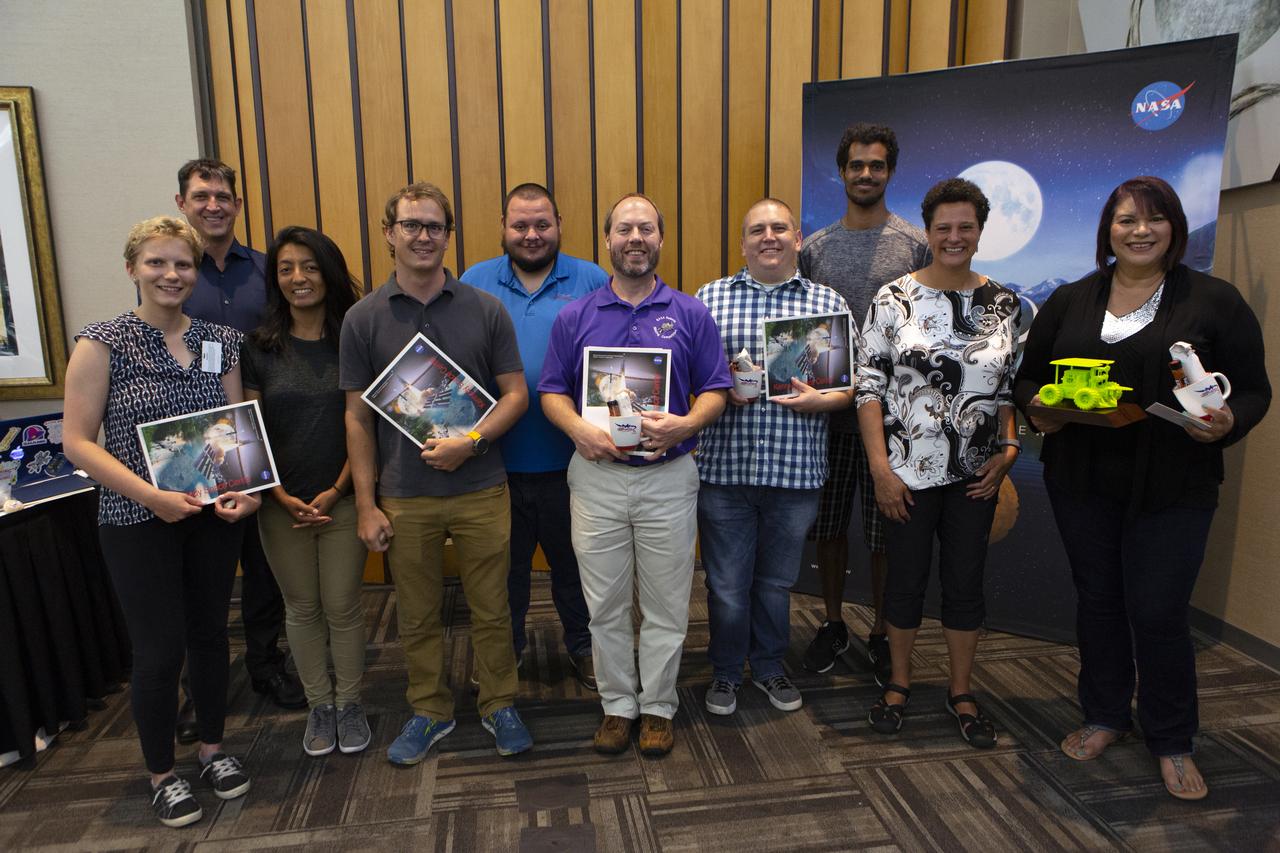During an awards ceremony on June 12, 2019 at the Kennedy Space Center Visitor Complex in Florida, mentors and volunteers from Kennedy received certificates of recognition for the NASA Swarmathon 2019 University Challenge. Second from right is Melanie Moses, a professor of computer science at the Swarmathon host location, University of New Mexico. At far right is Theresa Martinez, engagement manager of the Minority University Research and Education Program, managed at Kennedy. University students and their mentors were at Kennedy to participate in a student/mentor panel, hear from speakers, get a behind-the-scenes tour of Kennedy Space Center, dine with an astronaut and receive awards. During Swarmathon University Challenge IV, students developed algorithms for robotic swarms that are robust and adaptable like the foraging strategies of ant colonies. The fourth and final Swarmathon was a combined virtual and physical competition.