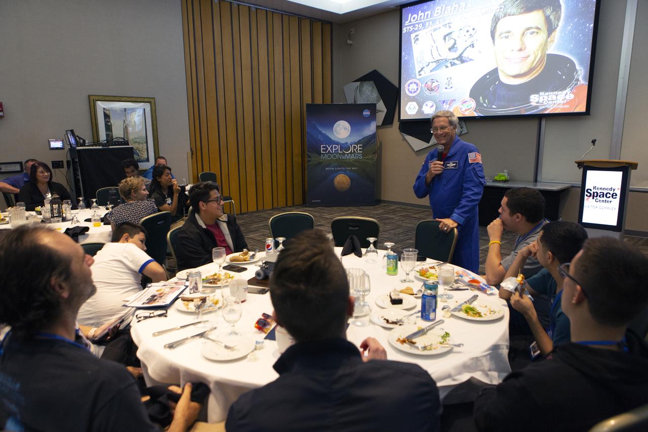 Retired NASA astronaut John Blaha talks to Swarmathon University Challenge students and their mentors during a Dine with an Astronaut event at the Kennedy Space Center Visitor Complex in Florida on June 12, 2019. Students and mentors from some of the Swarmathon teams were at Kennedy to participate in a student/mentor panel, hear from speakers, get a behind-the-scenes tour of Kennedy Space Center, dine with an astronaut and receive awards. For the challenge, university students developed algorithms for robotic swarms that are robust and adaptable like the foraging strategies of ant colonies. The fourth and final Swarmathon challenge was a combined virtual and physical competition hosted by the University of New Mexico.