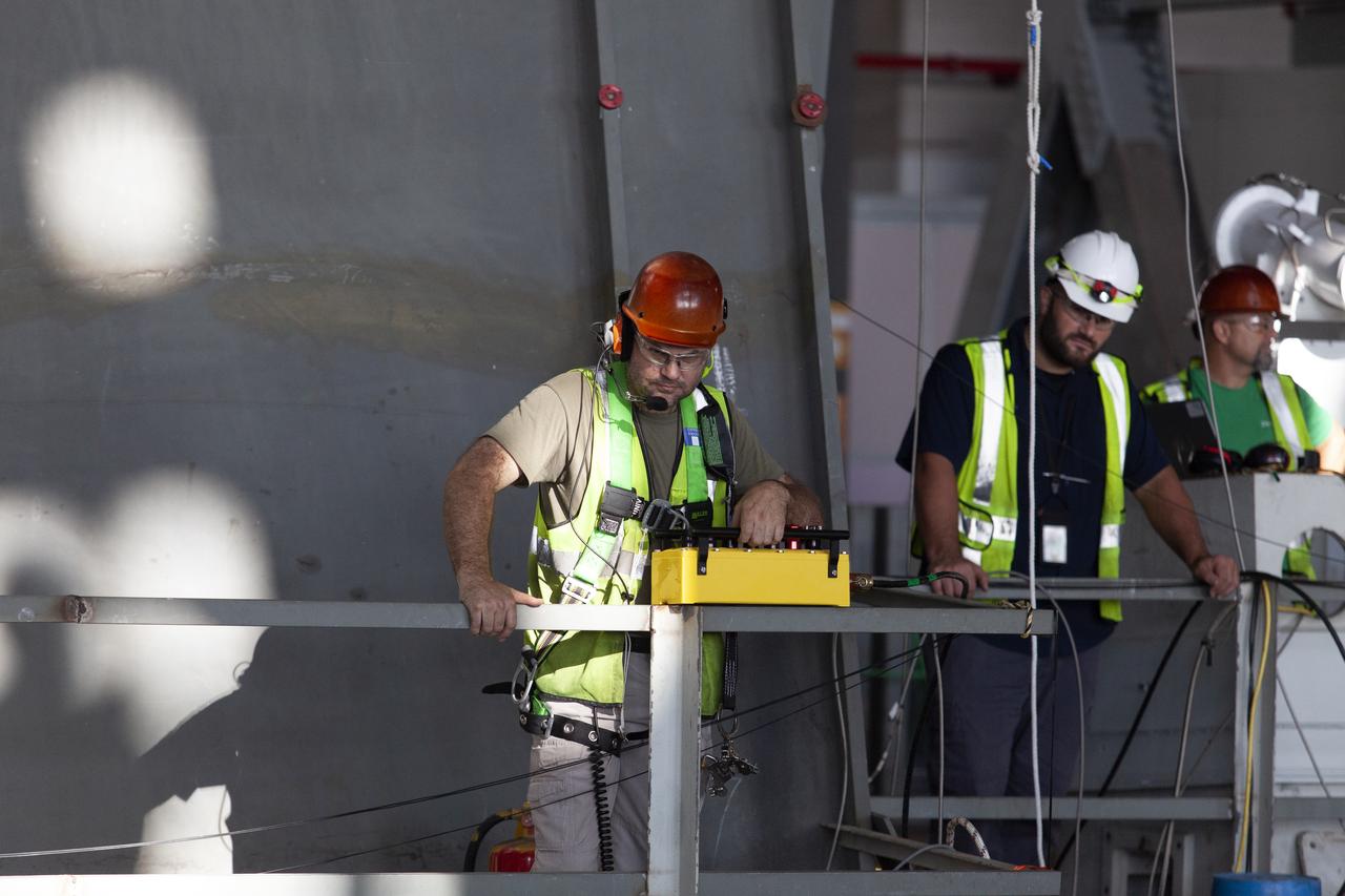 Jacobs TOSC workers prepare for the lift of the engine service platform that will provide access to the core stage of the Space Launch System (SLS) rocket on the mobile launcher (ML) in High Bay 3 of the Vehicle Assembly Building at NASA’s Kennedy Space Center in Florida on June 18, 2019. The large work platform is designed to provide unrestricted access to the RS-25 engines on the SLS core stage from the ML. The service platform will be used for Artemis 1 and subsequent missions. For Artemis 1, the Orion spacecraft will launch atop the SLS rocket from Launch Pad 39B and begin an approximately three-week mission that will send Orion thousands of miles beyond the Moon. Exploration Ground Systems is overseeing work on the ML.