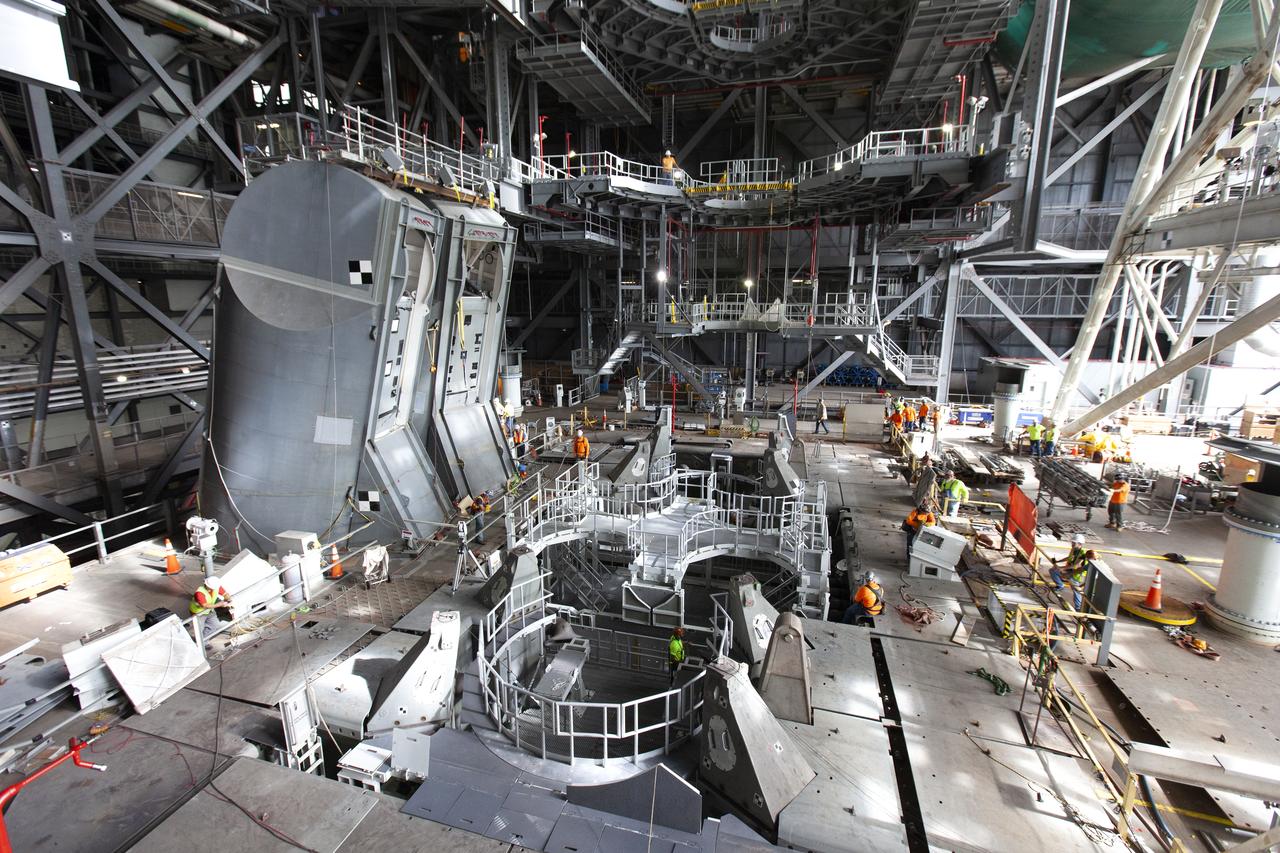 Inside the Vehicle Assembly Building at NASA’s Kennedy Space Center in Florida, the engine service platform that will provide access to the core stage of the Space Launch System (SLS) rocket is lifted up in the center of the mobile launcher (ML) in High Bay 3 on June 18, 2019. The large work platform is designed to provide unrestricted access to the RS-25 engines on the SLS core stage from the ML. The service platform will be used for Artemis 1 and subsequent missions. For Artemis 1, the Orion spacecraft will launch atop the SLS rocket from Launch Pad 39B and begin an approximately three-week mission that will send Orion thousands of miles beyond the Moon. In view at left are the two Tail Service Mast Umbilicals. They will provide liquid oxygen and liquid hydrogen fluid lines and electrical cable connections to the SLS core stage engine section. Exploration Ground Systems is overseeing work on the ML.