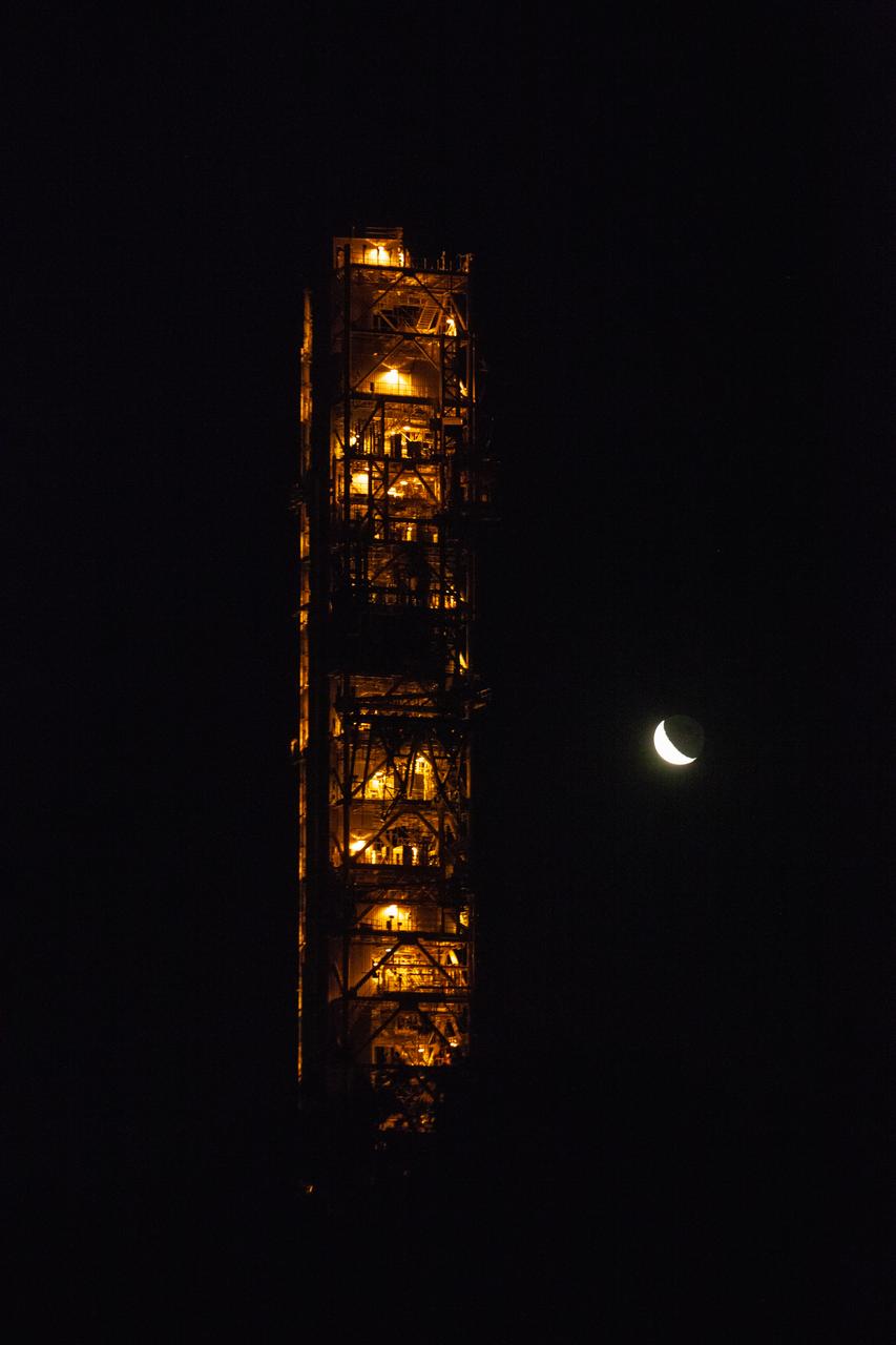 With the Moon and nighttime sky serving as the backdrop, Exploration Ground Systems’ mobile launcher is illuminated in the night as it makes its last solo trek to Kennedy Space Center’s Launch Complex 39B in Florida on June 27, 2019. The mobile launcher departed from the Vehicle Assembly Building at midnight on June 27 for the 10-hour journey to the pad, where it will remain for the summer, undergoing final testing and checkouts. Its next roll to the pad will be with the agency’s Space Launch System rocket and Orion spacecraft in preparation for the launch of Artemis 1. 