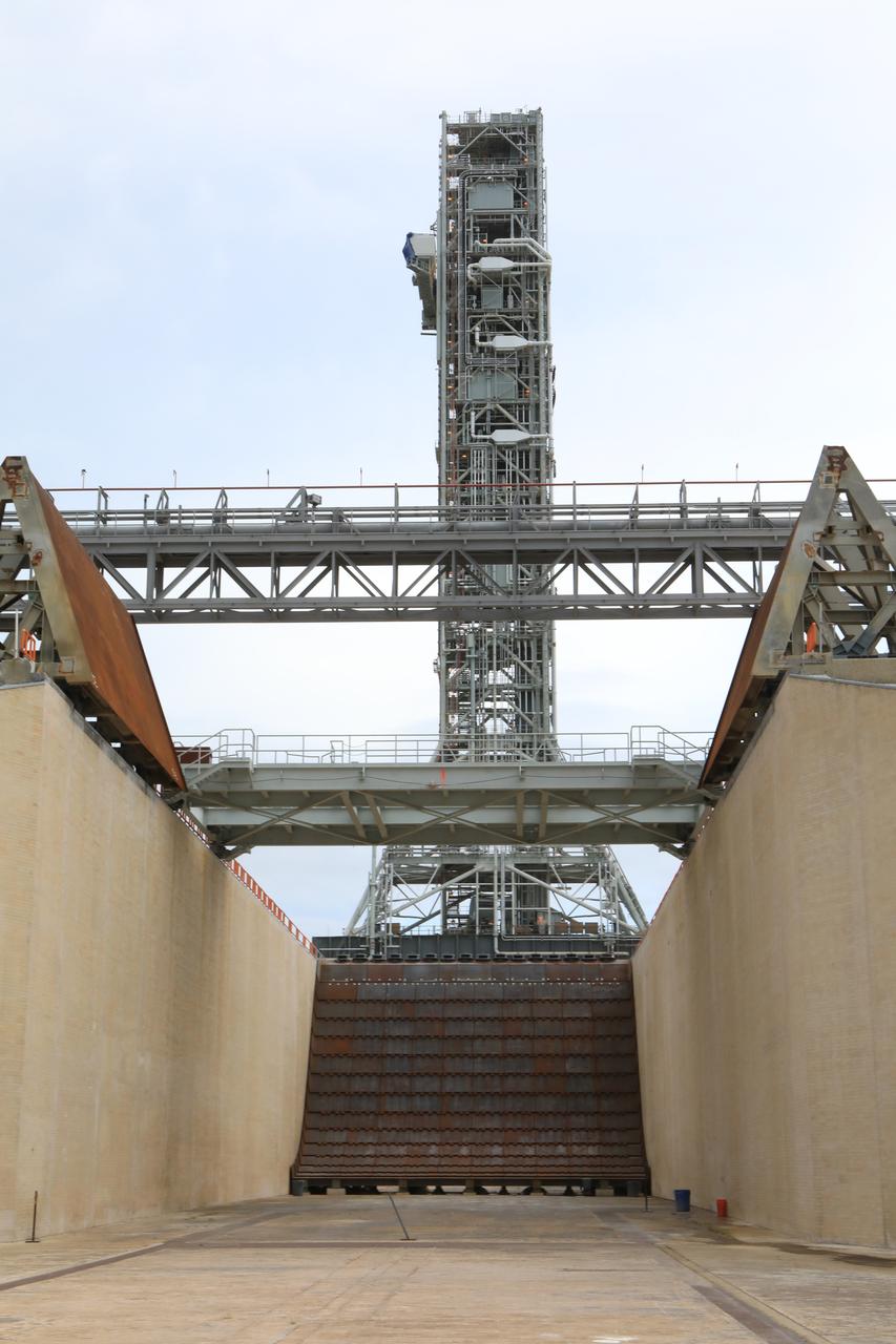In this view from the flame trench at Kennedy Space Center’s Launch Complex 39B in Florida, Exploration Ground Systems’ mobile launcher can be seen on the pad surface on June 28, 2019. The mobile launcher began its final solo trek – atop crawler-transporter 2 – to the pad at midnight on June 27, departing from NASA’s Vehicle Assembly Building and continuing up to the pad surface on June 28. The mobile launcher will remain at the pad over the summer, undergoing final testing and checkouts. Its next roll to the pad will be with the agency’s Space Launch System rocket and Orion in preparation for the launch of Artemis 1.