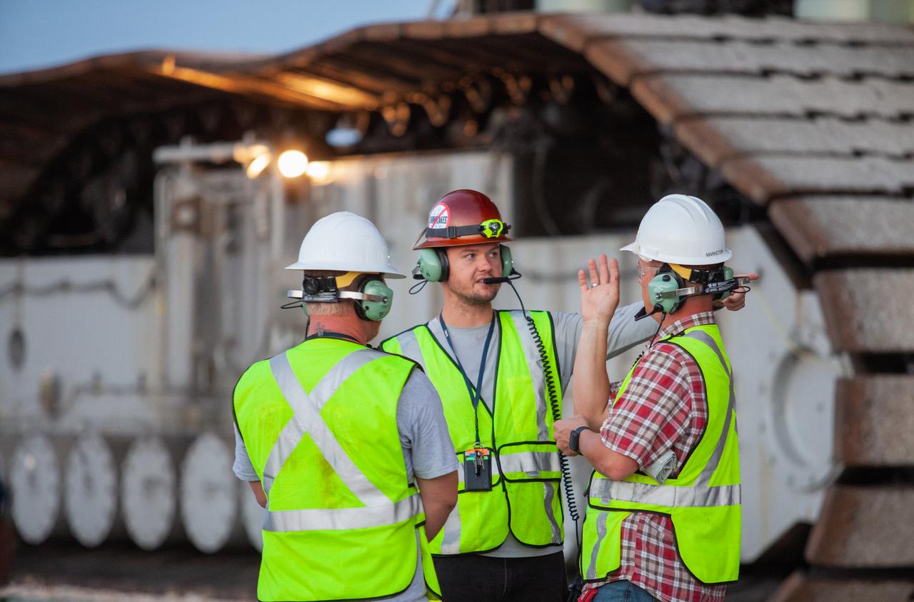 Kennedy Space Center employees stand near NASA’s crawler-transporter 2 at Kennedy’s Launch Complex 39B area in Florida on June 28, 2019. The crawler-transporter 2 successfully carried the Exploration Ground Systems’ mobile launcher to the pad from the Vehicle Assembly Building, departing at midnight on June 27. On June 28, the mobile launcher continued its journey up to the pad surface, where it will remain for the summer, undergoing final testing and checkouts. Its next roll to the pad will be with the agency’s Space Launch System rocket and Orion in preparation for the launch of Artemis 1.