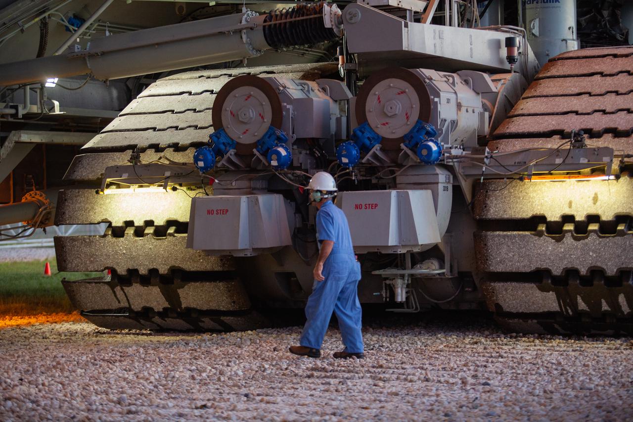 A Kennedy Space Center employee walks near NASA’s crawler-transporter 2 at Kennedy’s Launch Complex 39B area in Florida on June 28, 2019. The crawler-transporter 2 successfully carried Exploration Ground Systems’ mobile launcher to the pad from the Vehicle Assembly Building, departing at midnight on June 27. On June 28, the mobile launcher continued its journey up to the pad surface, where it will remain for the summer, undergoing final testing and checkouts. Its next roll to the pad will be with the agency’s Space Launch System rocket and Orion in preparation for the launch of Artemis 1. 