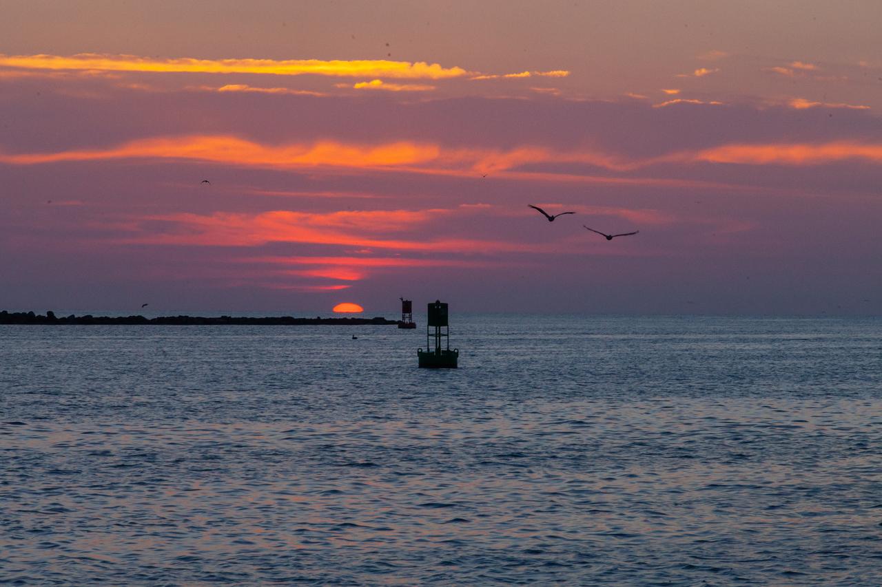 A view of the sunrise at Jetty Park in Cape Canaveral, Florida, on July 2, 2019, as crowds gather to watch a Northrop Grumman provided booster launch from Launch Pad 46 carrying, a fully functional Launch Abort System with a test version of Orion attached for NASA’s Ascent Abort-2 (AA-2). Launch time was 7 a.m. EDT. During AA-2, the booster will send the LAS and Orion to an altitude of 31,000 feet, traveling at Mach 1.15 (more than 1,000 mph). The LAS’ three motors will work together to pull the crew module away from the booster and prepare it for splashdown in the Atlantic Ocean. The flight test will prove that the abort system can pull crew to safety in the unlikely event of an emergency during ascent.