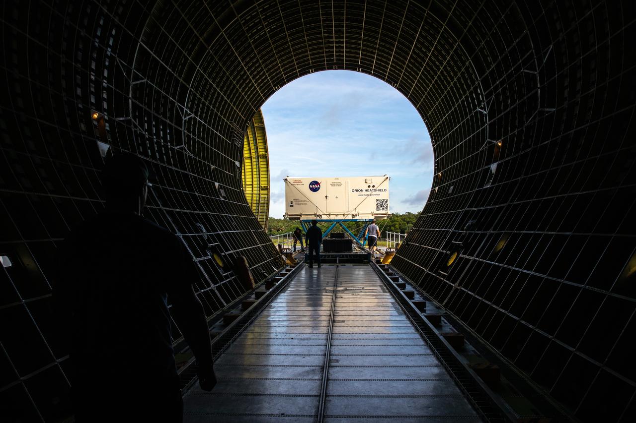 In this view from inside NASA’s Super Guppy aircraft, the shipping container carrying the heat shield for Orion’s Artemis 2 mission, NASA’s first crewed mission, is unloaded from NASA’s Super Guppy aircraft at the agency’s Kennedy Space Center Shuttle Landing Facility in Florida on July 9, 2019. The heat shield, measuring roughly 16 feet in diameter, will protect astronauts upon re-entry on the second mission of Artemis. The heat shield arrived from Lockheed Martin’s manufacturing facility near Denver. It will be delivered to the Neil Armstrong Operations and Checkout facility high bay. The heat shield is a base titanium truss structure. Over the next several months, technicians will apply Avcoat, an ablative material that will provide the thermal protection. Artemis 2 will confirm all of the spacecraft’s systems operate as designed in the actual environment of deep space with astronauts aboard.