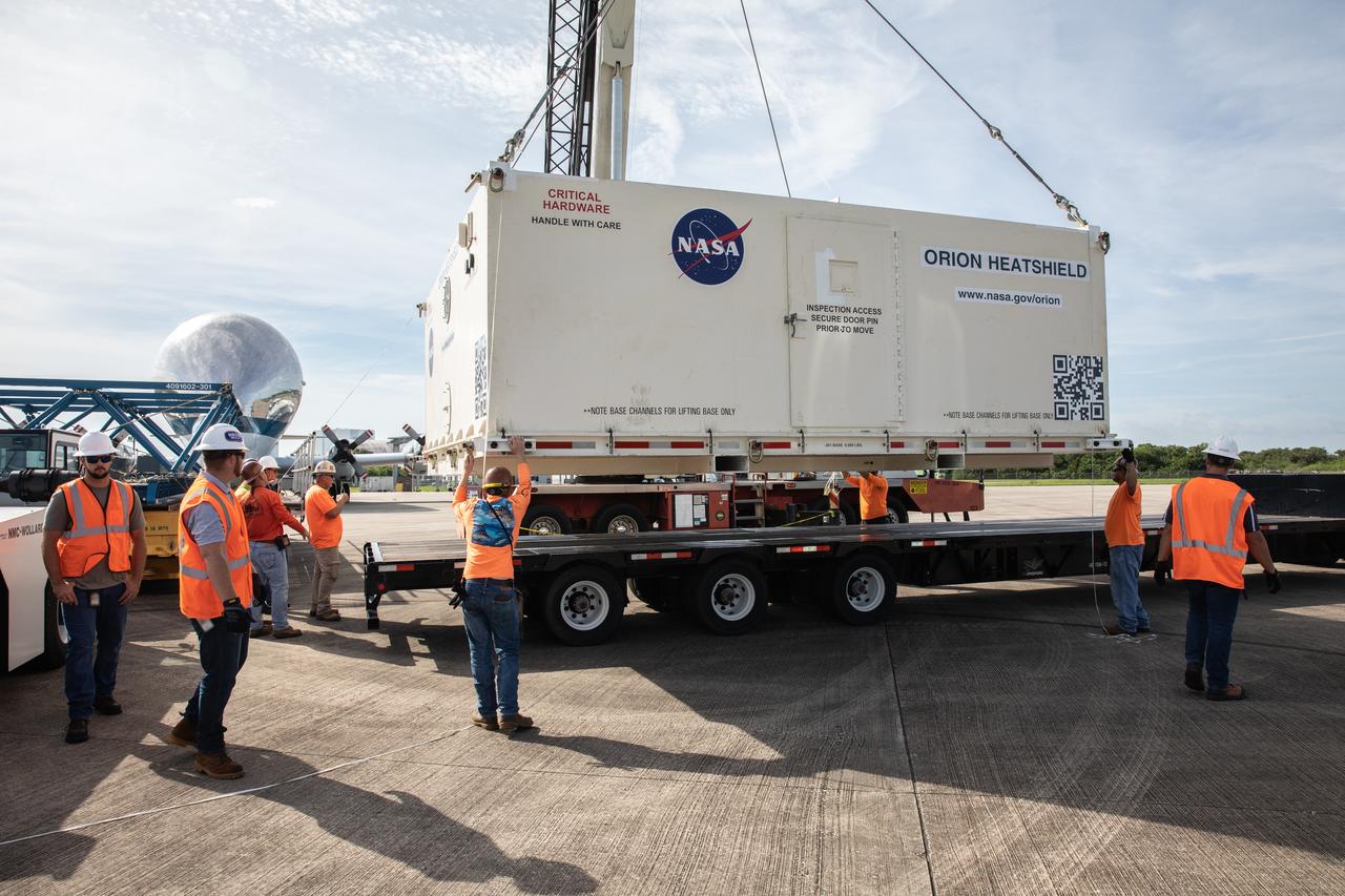 Technicians help secure the shipping container carrying the heat shield for Orion’s Artemis 2 mission, NASA’s first crewed mission, onto a transporter at the agency’s Kennedy Space Center Shuttle Landing Facility in Florida on July 9, 2019. The heat shield, measuring roughly 16 feet in diameter, will protect astronauts upon re-entry on the second mission of Artemis. The heat shield arrived from Lockheed Martin’s manufacturing facility near Denver aboard NASA’s Super Guppy Aircraft. It will be delivered to the Neil Armstrong Operations and Checkout facility high bay. The heat shield is a base titanium truss structure. Over the next several months, technicians will apply Avcoat, an ablative material that will provide the thermal protection. Artemis 2 will confirm all of the spacecraft’s systems operate as designed in the actual environment of deep space with astronauts aboard.