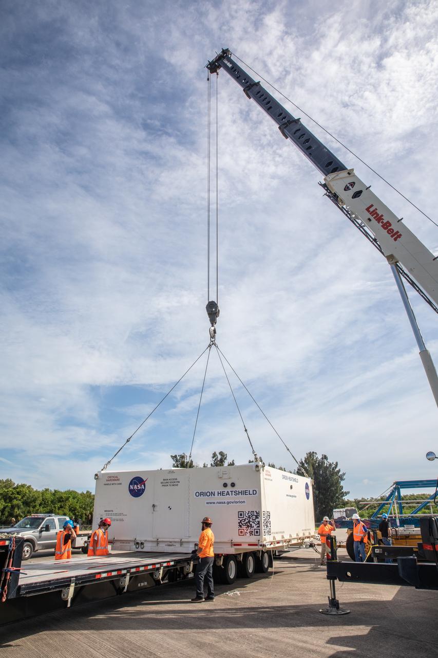 Technicians help secure the shipping container carrying the heat shield for Orion’s Artemis 2 mission, NASA’s first crewed mission, onto a transporter at the agency’s Kennedy Space Center Shuttle Landing Facility in Florida on July 9, 2019. The heat shield, measuring roughly 16 feet in diameter, will protect astronauts upon re-entry on the second mission of Artemis. The heat shield arrived from Lockheed Martin’s manufacturing facility near Denver aboard NASA’s Super Guppy Aircraft. It will be delivered to the Neil Armstrong Operations and Checkout facility high bay. The heat shield is a base titanium truss structure. Over the next several months, technicians will apply Avcoat, an ablative material that will provide the thermal protection. Artemis 2 will confirm all of the spacecraft’s systems operate as designed in the actual environment of deep space with astronauts aboard.