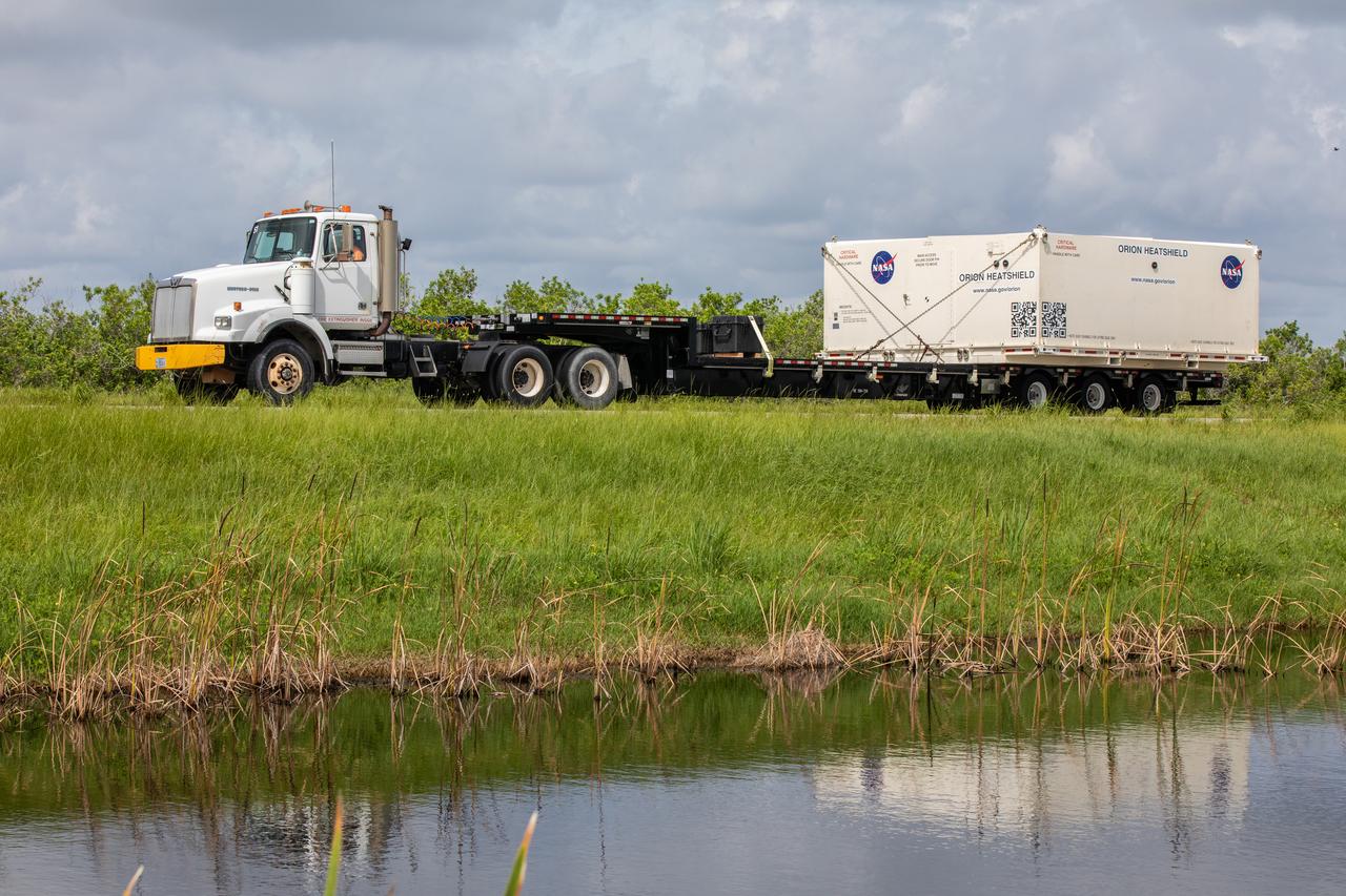 A flatbed truck with the shipping container carrying the heat shield for Orion’s Artemis 2 mission, NASA’s first crewed mission, departs the agency’s Kennedy Space Center Shuttle Landing Facility in Florida on July 9, 2019. The heat shield, measuring roughly 16 feet in diameter, will protect astronauts upon re-entry on the second mission of Artemis. The heat shield arrived from Lockheed Martin’s manufacturing facility near Denver aboard NASA’s Super Guppy Aircraft. It will be delivered to the Neil Armstrong Operations and Checkout facility high bay. The heat shield is a base titanium truss structure. Over the next several months, technicians will apply Avcoat, an ablative material that will provide the thermal protection. Artemis 2 will confirm all of the spacecraft’s systems operate as designed in the actual environment of deep space with astronauts aboard.