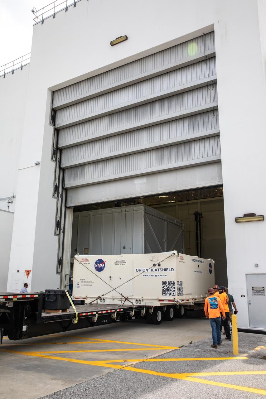 A flatbed truck with the shipping container carrying the heat shield for Orion’s Artemis 2 mission, NASA’s first crewed mission, arrives at the Neil Armstrong Operations and Checkout Building high bay entrance at the agency’s Kennedy Space Center in Florida on July 9, 2019. The heat shield, measuring roughly 16 feet in diameter, will protect astronauts upon re-entry on the second mission of Artemis. The heat shield arrived from Lockheed Martin’s manufacturing facility near Denver aboard NASA’s Super Guppy Aircraft. The heat shield is a base titanium truss structure. Over the next several months, technicians will apply Avcoat, an ablative material that will provide the thermal protection. Artemis 2 will confirm all of the spacecraft’s systems operate as designed in the actual environment of deep space with astronauts aboard.