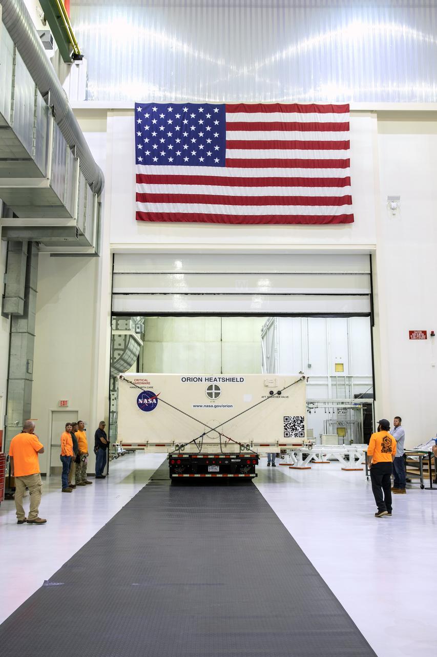 A flatbed truck with the shipping container carrying the heat shield for Orion’s Artemis 2 mission, NASA’s first crewed mission, moves into the Neil Armstrong Operations and Checkout Building high bay at the agency’s Kennedy Space Center in Florida on July 9, 2019. The heat shield, measuring roughly 16 feet in diameter, will protect astronauts upon re-entry on the second mission of Artemis. The heat shield arrived from Lockheed Martin’s manufacturing facility near Denver aboard NASA’s Super Guppy Aircraft. The heat shield is a base titanium truss structure. Over the next several months, technicians will apply Avcoat, an ablative material that will provide the thermal protection. Artemis 2 will confirm all of the spacecraft’s systems operate as designed in the actual environment of deep space with astronauts aboard.