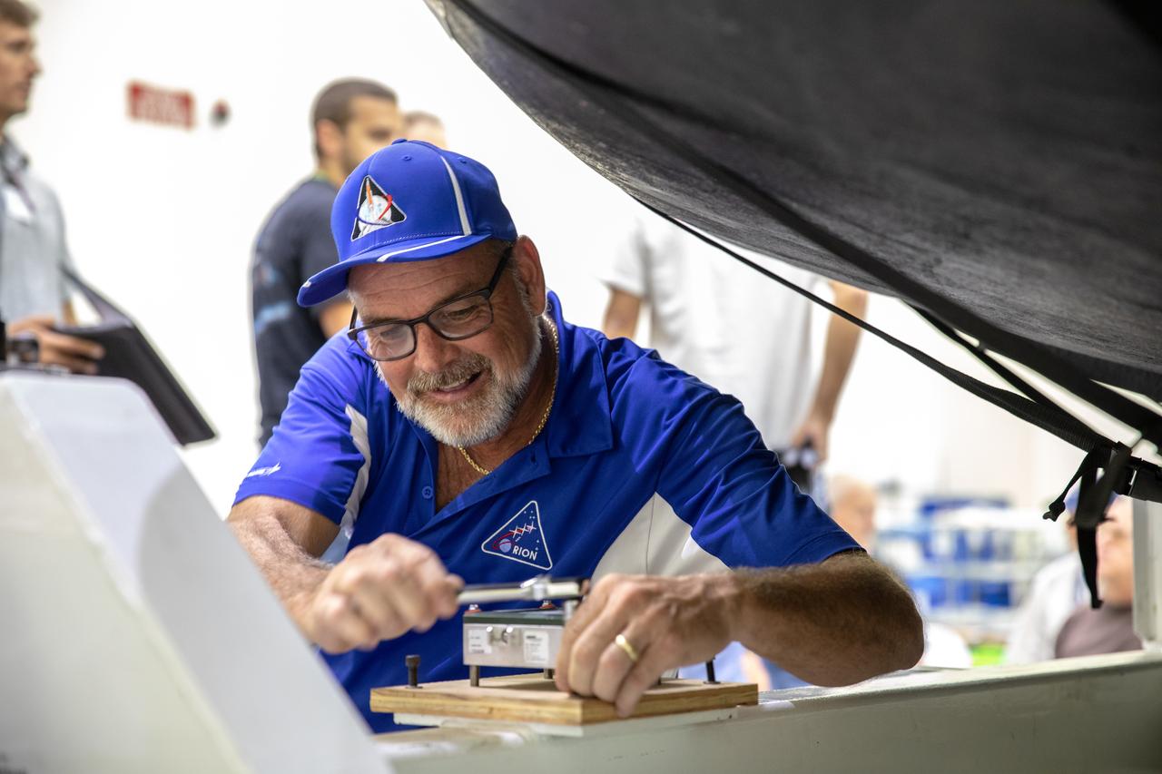 A Lockheed Martin technician works to remove a bolt that holds the heat shield for Orion’s Artemis 2 mission, NASA’s first crewed mission, on its shipping platform inside the Neil Armstrong Operations and Checkout Building high bay at the agency’s Kennedy Space Center in Florida on July 10, 2019. The heat shield, measuring roughly 16 feet in diameter, will protect astronauts upon re-entry on the second mission of Artemis. The heat shield arrived from Lockheed Martin’s manufacturing facility near Denver aboard NASA’s Super Guppy Aircraft. The heat shield is a base titanium truss structure. Over the next several months, technicians will apply Avcoat, an ablative material that will provide the thermal protection. Artemis 2 will confirm all of the spacecraft’s systems operate as designed in the actual environment of deep space with astronauts aboard.