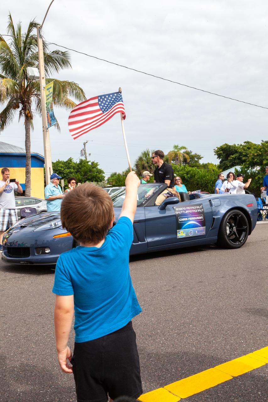 A child waves an Amercan Flag as Boeing astronaut Chris Ferguson rides by in a Corvette during the “Man on the Moon” astronaut parade in Cocoa Beach, Florida, on July 13, 2019. The parade was held to honor the 50th anniversary of NASA’s Saturn V/Apollo 11 launch and landing on the Moon.
