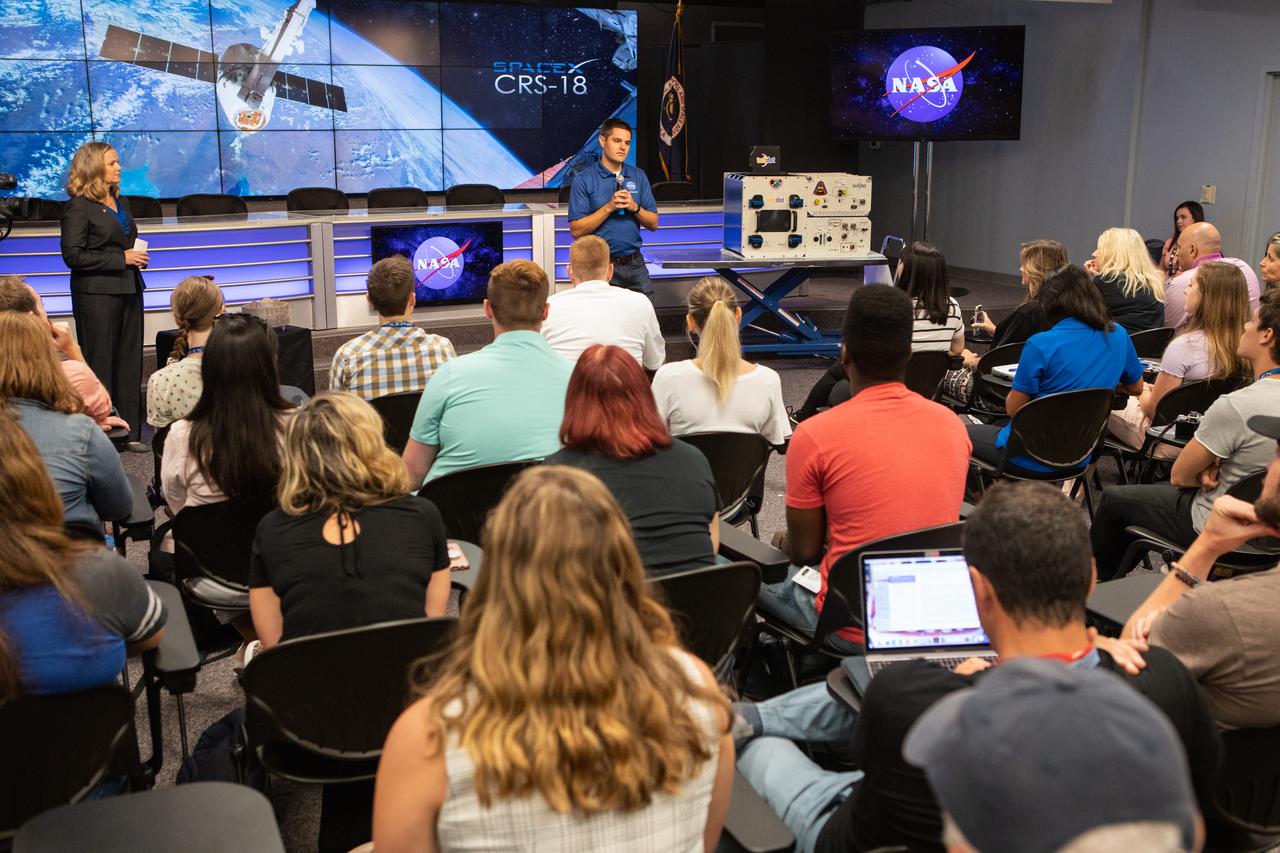 Jason August, International Space Station Mission Evaluation Room manager, talks to NASA Social participants about the International Docking Adapter-3 payload during a What’s On Board science briefing at the agency’s Kennedy Space Center in Florida on July 23, 2019.  The briefing was held for SpaceX’s 18th Commercial Resupply Services (CRS-18) mission to the station. The SpaceX Falcon 9 rocket and uncrewed Dragon spacecraft are scheduled to launch July 24, 2019, from Space Launch Complex 40 at Florida’s Cape Canaveral Air Force Station. 