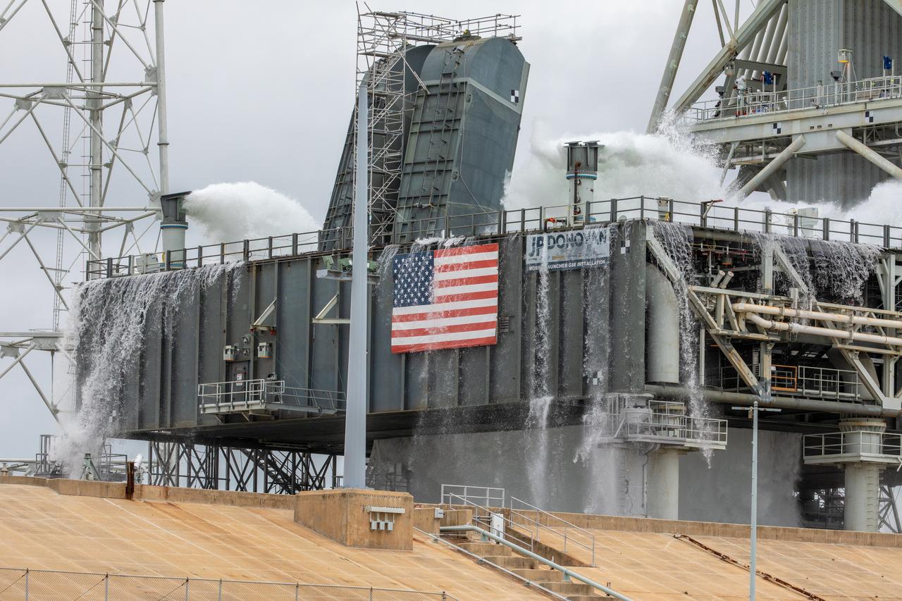 A flow test of the Ignition Overpressure Protection and Sound Suppression water deluge system begins on the mobile launcher at Launch Pad 39B at NASA's Kennedy Space Center in Florida, on July 25, 2019. The testing is part of a series of tests that Exploration Ground System is doing to verify the system is ready for the new Space Launch System rocket. Modifications were made to the pad after a previous wet flow test, increasing the performance of the system. During the launch of Artemis 1 and subsequent missions, this water deluge system will release about 450,000 gallons of water across the mobile launcher and Flame Deflector to reduce the extreme heat and energy generated by the rocket during ignition and liftoff.