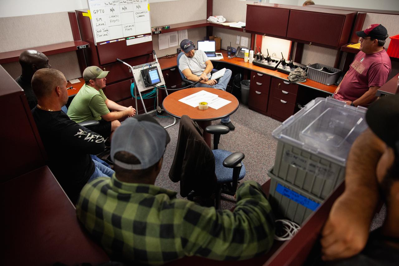Inside the Multi-Operations Support Building near the Multi-Payload Processing Facility (MPPF) at NASA’s Kennedy Space Center in Florida, technicians and operations personnel review procedures for a test simulation of loading propellants into a replicated test tank for Orion, on Aug. 16, 2019. Exploration Ground Systems is preparing for Artemis 1 with a series of hazardous hyper test events at the MPPF. Technicians will practice putting on Self-Contained Atmospheric Protective Ensemble (SCAPE) suits and then complete tanking to test the system before Orion arrives for processing. During preparations for launch, these teams will be responsible for loading the Orion vehicle with propellants prior to transportation to the Vehicle Assembly Building, where it will be secured atop the Space Launch System rocket. SCAPE suits are used in operations involving toxic propellants and are supplied with air either through a hardline or through a self-contained environmental control unit.