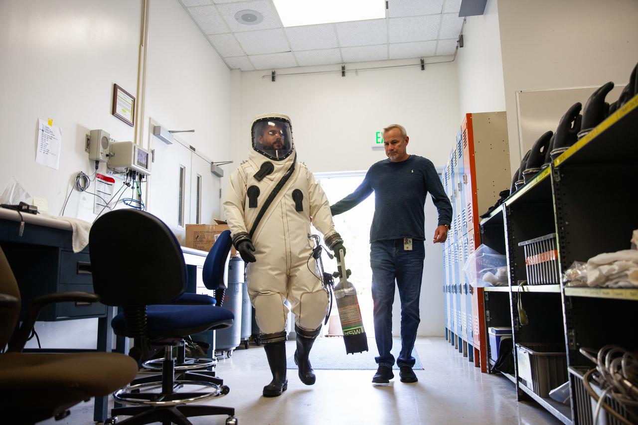 Inside the Multi-Operations Support Building near the Multi-Payload Processing Facility (MPPF) at NASA’s Kennedy Space Center in Florida, a technician is wearing a Self-Contained Atmospheric Protective Ensemble (SCAPE) suit to prepare for a test simulation of loading propellants into a replicated test tank for Orion, on Aug. 16, 2019. Exploration Ground Systems is preparing for Artemis 1 with a series of hazardous hyper test events at the MPPF. After donning their suits, the technicians will complete tanking to test the system before Orion arrives for processing. During preparations for launch, these teams will be responsible for loading the Orion vehicle with propellants prior to transportation to the Vehicle Assembly Building, where it will be secured atop the Space Launch System rocket. SCAPE suits are used in operations involving toxic propellants and are supplied with air either through a hardline or through a self-contained environmental control unit.