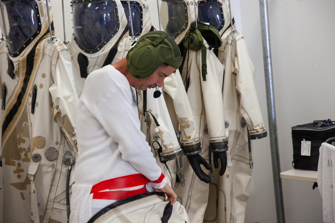Inside the Multi-Operations Support Building near the Multi-Payload Processing Facility (MPPF) at NASA’s Kennedy Space Center in Florida, a technician prepares to put on a Self-Contained Atmospheric Protective Ensemble (SCAPE) suit inside a changing room on Aug. 16, 2019. SCAPE technicians are practicing putting on the suits for a test simulation of loading propellants into a replicated test tank for Orion. Exploration Ground Systems is preparing for Artemis 1 with a series of hazardous hyper test events at the MPPF. After donning their suits, the technicians will complete a tanking to test the system before Orion arrives for processing. During preparations for launch, these teams will be responsible for loading the Orion vehicle with propellants prior to transportation to the Vehicle Assembly Building, where it will be secured atop the Space Launch System rocket. SCAPE suits are used in operations involving toxic propellants and are supplied with air either through a hardline or through a self-contained environmental control unit.