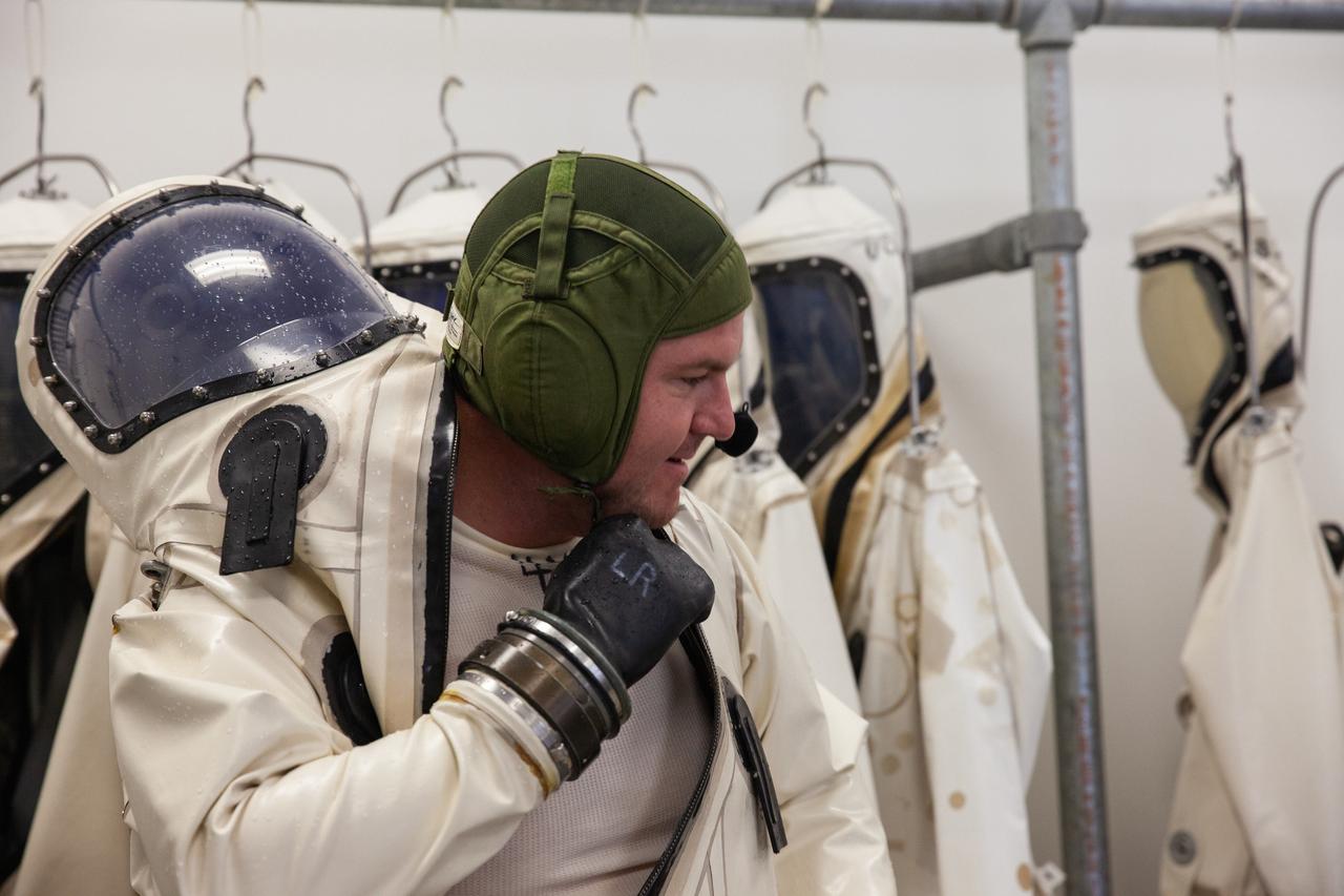 Inside the Multi-Operations Support Building near the Multi-Payload Processing Facility (MPPF) at NASA’s Kennedy Space Center in Florida, a technician puts on a Self-Contained Atmospheric Protective Ensemble (SCAPE) suit inside a changing room on Aug. 16, 2019. SCAPE technicians are practicing putting on the suits for a test simulation of loading propellants into a replicated test tank for Orion. Exploration Ground Systems is preparing for Artemis 1 with a series of hazardous hyper test events at the MPPF. After donning their suits, the technicians will complete a tanking to test the system before Orion arrives for processing. During preparations for launch, these teams will be responsible for loading the Orion vehicle with propellants prior to transportation to the Vehicle Assembly Building, where it will be secured atop the Space Launch System rocket. SCAPE suits are used in operations involving toxic propellants and are supplied with air either through a hardline or through a self-contained environmental control unit.