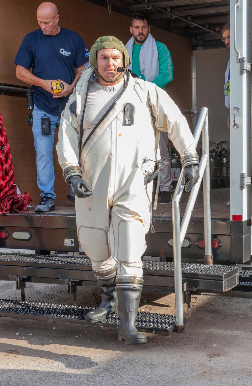 A technician in a Self-Contained Atmospheric Protective Ensemble (SCAPE) suit exits a truck near the Multi-Payload Processing Facility (MPPF) at NASA’s Kennedy Space Center in Florida on Aug. 16, 2019. SCAPE technicians are practicing by putting on the suits for a test simulation of loading propellants into a replicated test tank for Orion. Exploration Ground Systems is preparing for Artemis 1 with a series of hazardous hyper test events at the MPPF. After donning their suits, the technicians will complete a tanking to test the system before Orion arrives for processing. During preparations for launch, these teams will be responsible for loading the Orion vehicle with propellants prior to transportation to the Vehicle Assembly Building, where it will be secured atop the Space Launch System rocket. SCAPE suits are used in operations involving toxic propellants and are supplied with air either through a hardline or through a self-contained environmental control unit.