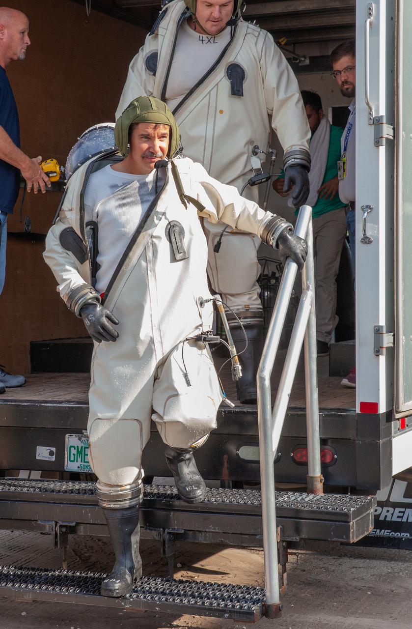 Technicians in Self-Contained Atmospheric Protective Ensemble (SCAPE) suits exit a truck near the Multi-Payload Processing Facility (MPPF) at NASA’s Kennedy Space Center in Florida, for a test simulation of loading propellants into a replicated test tank for Orion on Aug. 16, 2019. Exploration Ground Systems is preparing for Artemis 1 with a series of hazardous hyper test events at the MPPF. The technicians will complete a tanking to test the system before Orion arrives for processing. During preparations for launch, these teams will be responsible for loading the Orion vehicle with propellants prior to transportation to the Vehicle Assembly Building, where it will be secured atop the Space Launch System rocket. SCAPE suits are used in operations involving toxic propellants and are supplied with air either through a hardline or through a self-contained environmental control unit.