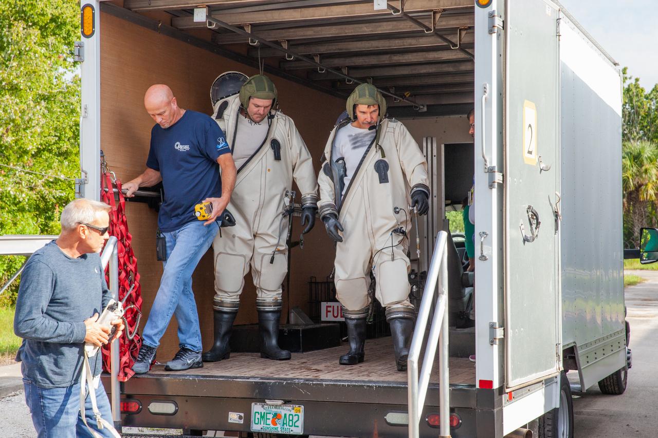 Technicians in Self-Contained Atmospheric Protective Ensemble (SCAPE) suits exit a truck near the Multi-Payload Processing Facility (MPPF) at NASA’s Kennedy Space Center in Florida, for a test simulation of loading propellants into a replicated test tank for Orion on Aug. 16, 2019. Exploration Ground Systems is preparing for Artemis 1 with a series of hazardous hyper test events at the MPPF. The technicians will complete a tanking to test the system before Orion arrives for processing. During preparations for launch, these teams will be responsible for loading the Orion vehicle with propellants prior to transportation to the Vehicle Assembly Building, where it will be secured atop the Space Launch System rocket. SCAPE suits are used in operations involving toxic propellants and are supplied with air either through a hardline or through a self-contained environmental control unit.