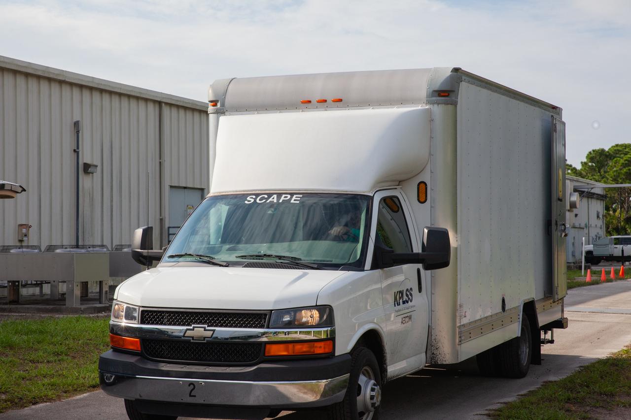 A truck transports technicians wearing Self-Contained Atmospheric Protective Ensemble (SCAPE) suits and operations support personnel to the Multi-Payload Processing Facility (MPPF) at NASA’s Kennedy Space Center in Florida, for a test simulation of loading propellants into a replicated test tank for Orion on Aug. 16, 2019. Exploration Ground Systems is preparing for Artemis 1 with a series of hazardous hyper test events at the MPPF. The technicians will complete a tanking to test the system before Orion arrives for processing. During preparations for launch, these teams will be responsible for loading the Orion vehicle with propellants prior to transportation to the Vehicle Assembly Building, where it will be secured atop the Space Launch System rocket. SCAPE suits are used in operations involving toxic propellants and are supplied with air either through a hardline or through a self-contained environmental control unit.