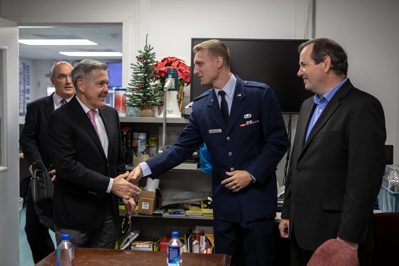 Just before a ribbon cutting ceremony on Aug. 16, 2019, in High Bay 2 of the Vehicle Assembly (VAB) at NASA’s Kennedy Space Center in Florida, Center Director Bob Cabana, at left, shakes hands with First Lieutenant Alex Priesser, U.S. Air Force, 45th Space Wing. At far right is Jim Williams, director of media operations, 45th Space Wing. The VAB is getting its first commercial tenant. Northrop Grumman signed a Reimbursable Space Act Agreement with NASA for use of the facilities. The company will assemble and test its new OmegA rocket inside the massive facility’s High Bay 2. The company also will modify the space shuttle-era mobile launcher platform-3 to serve as the launch vehicle’s assembly and launch platform. Northrop Grumman is developing the OmegA rocket, an intermediate/heavy-class launch vehicle, as part of a launch services agreement with the U.S. Air Force.