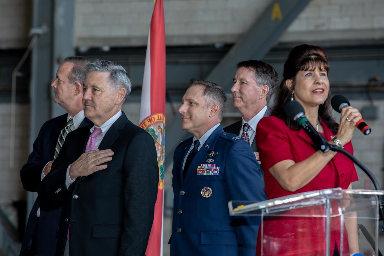 The National Anthem is sung by Suzy Cunningham, NASA Strategy and Integration manager, during a ribbon cutting ceremony on Aug. 16, 2019, in High Bay 2 of the Vehicle Assembly Building (VAB) at NASA’s Kennedy Space Center in Florida. From left are Tom Engler, director of Kennedy’s Center Planning and Development Office; Kennedy’s Center Director Bob Cabana; Col. Thomas Ste. Marie, vice commander, U.S. Air Force, 45th Space Wing; and Kent Rominger, Northrop Grumman’s vice president and capture lead for the OmegA launch system. The VAB is getting its first commercial tenant. Northrop Grumman signed a Reimbursable Space Act Agreement with NASA for use of the facilities. The company will assemble and test its new OmegA rocket inside the massive facility’s High Bay 2. The company also will modify mobile launcher platform-3 to serve as the launch vehicle’s assembly and launch platform. Northrop Grumman is developing the OmegA rocket, an intermediate/heavy-class launch vehicle, as part of a launch services agreement with the U.S. Air Force.