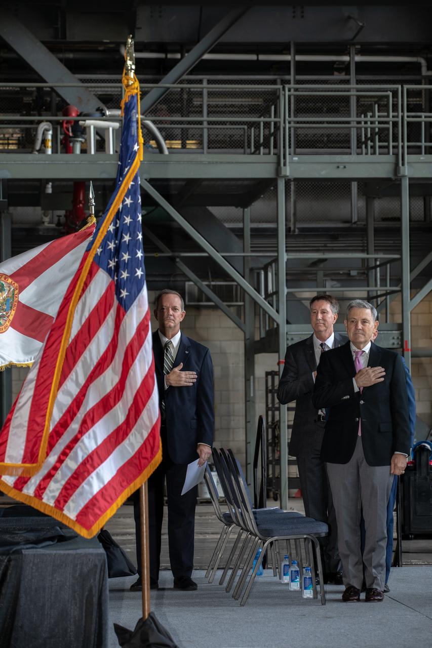 The National Anthem is sung during a ribbon cutting ceremony on Aug. 16, 2019, in High Bay 2 of the Vehicle Assembly Building (VAB) at NASA’s Kennedy Space Center in Florida. From left are Tom Engler, director of Kennedy’s Center Planning and Development Office; Kent Rominger, Northrop Grumman’s vice president and capture lead for the OmegA launch system; and Kennedy’s Center Director Bob Cabana. The VAB is getting its first commercial tenant. Northrop Grumman signed a Reimbursable Space Act Agreement with NASA for use of the facilities. The company will assemble and test its new OmegA rocket inside the massive facility’s High Bay 2. The company also will modify mobile launcher platform-3 to serve as the launch vehicle’s assembly and launch platform. Northrop Grumman is developing the OmegA rocket, an intermediate/heavy-class launch vehicle, as part of a launch services agreement with the U.S. Air Force. 